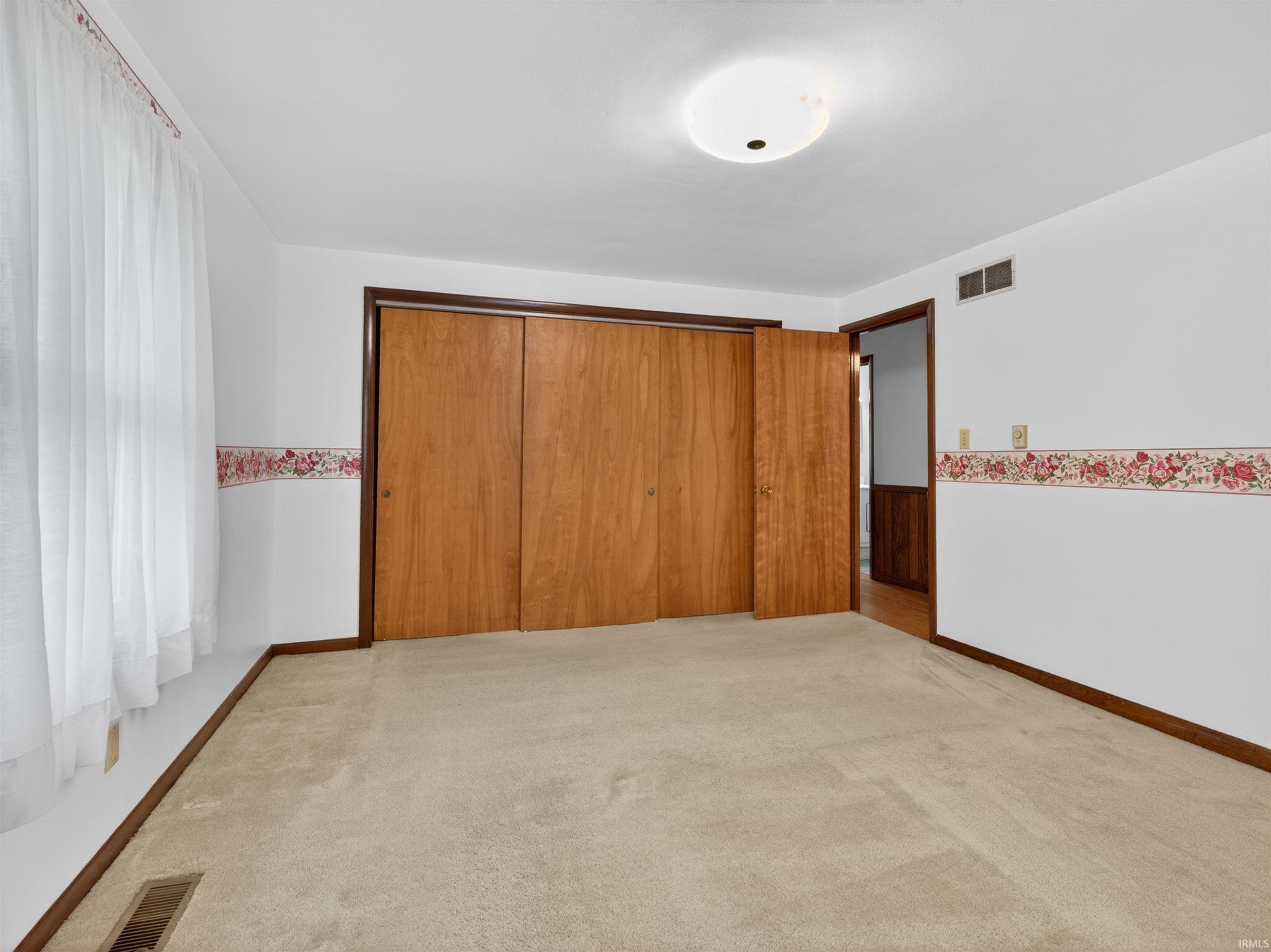 Light-colored carpeting complements white walls with a decorative floral border
