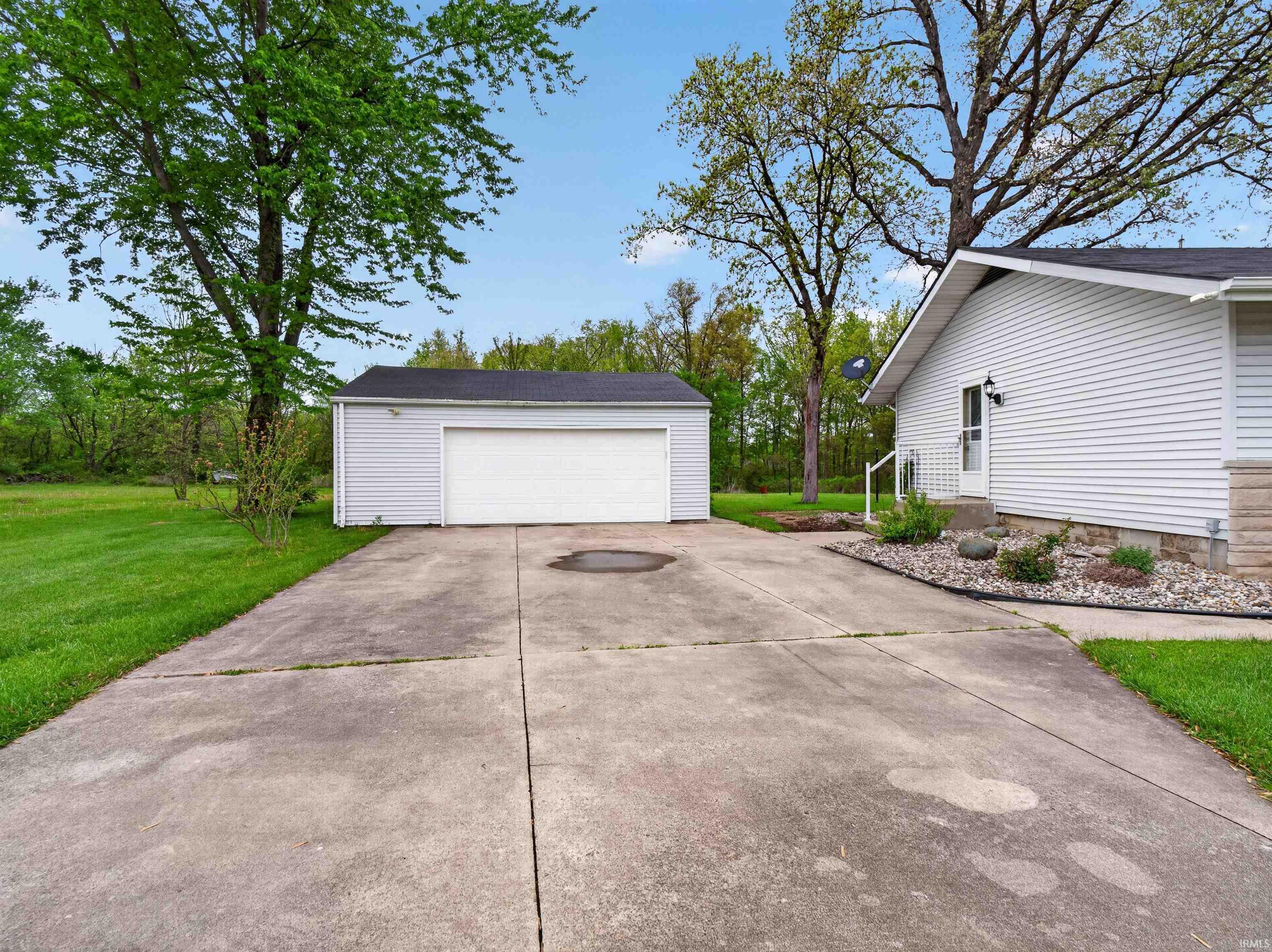 Expansive concrete driveway leading to a detached garage and a side entry home
