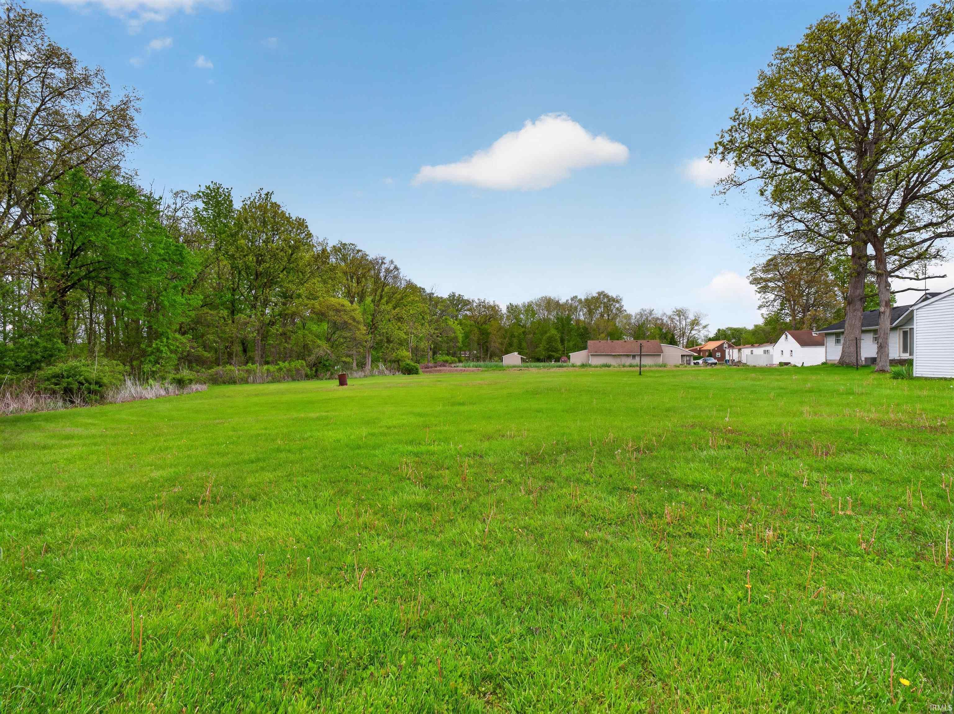 Expansive green lawn with mature trees bordering the property