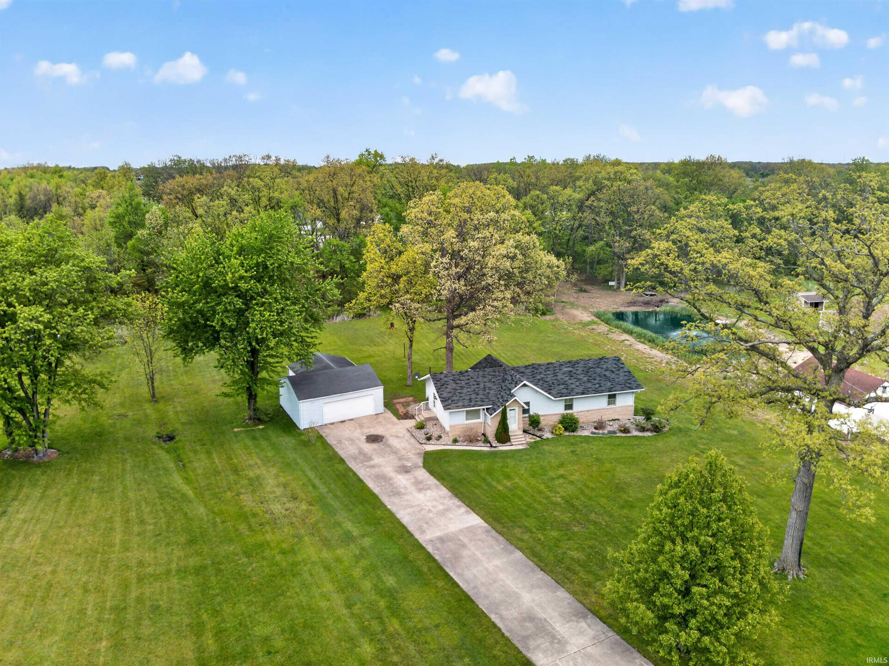 Ranch-style residence featuring a paved driveway, detached garage, and a pond