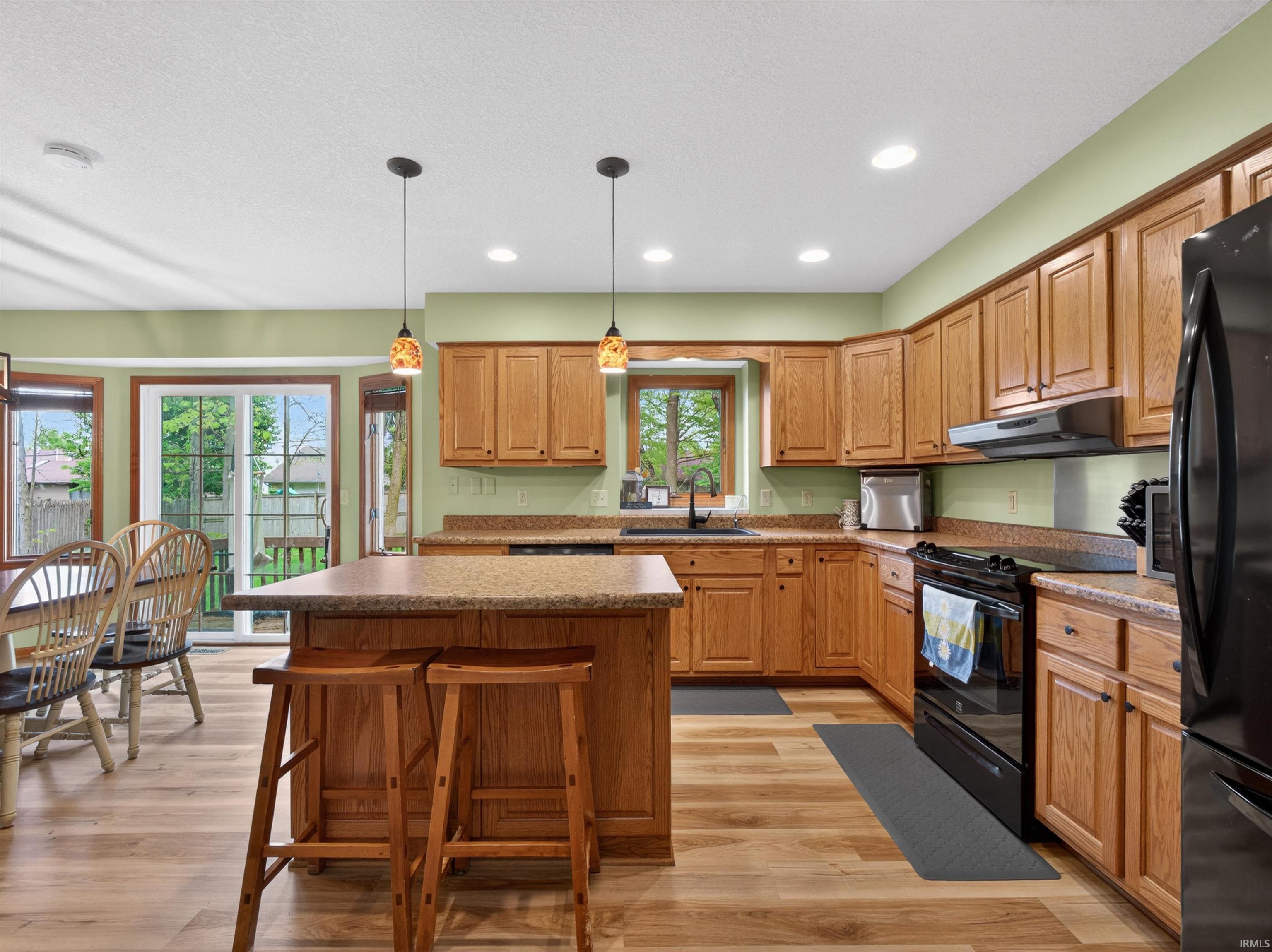 Kitchen featuring light wood cabinetry, stone-look countertops, and an island with seating