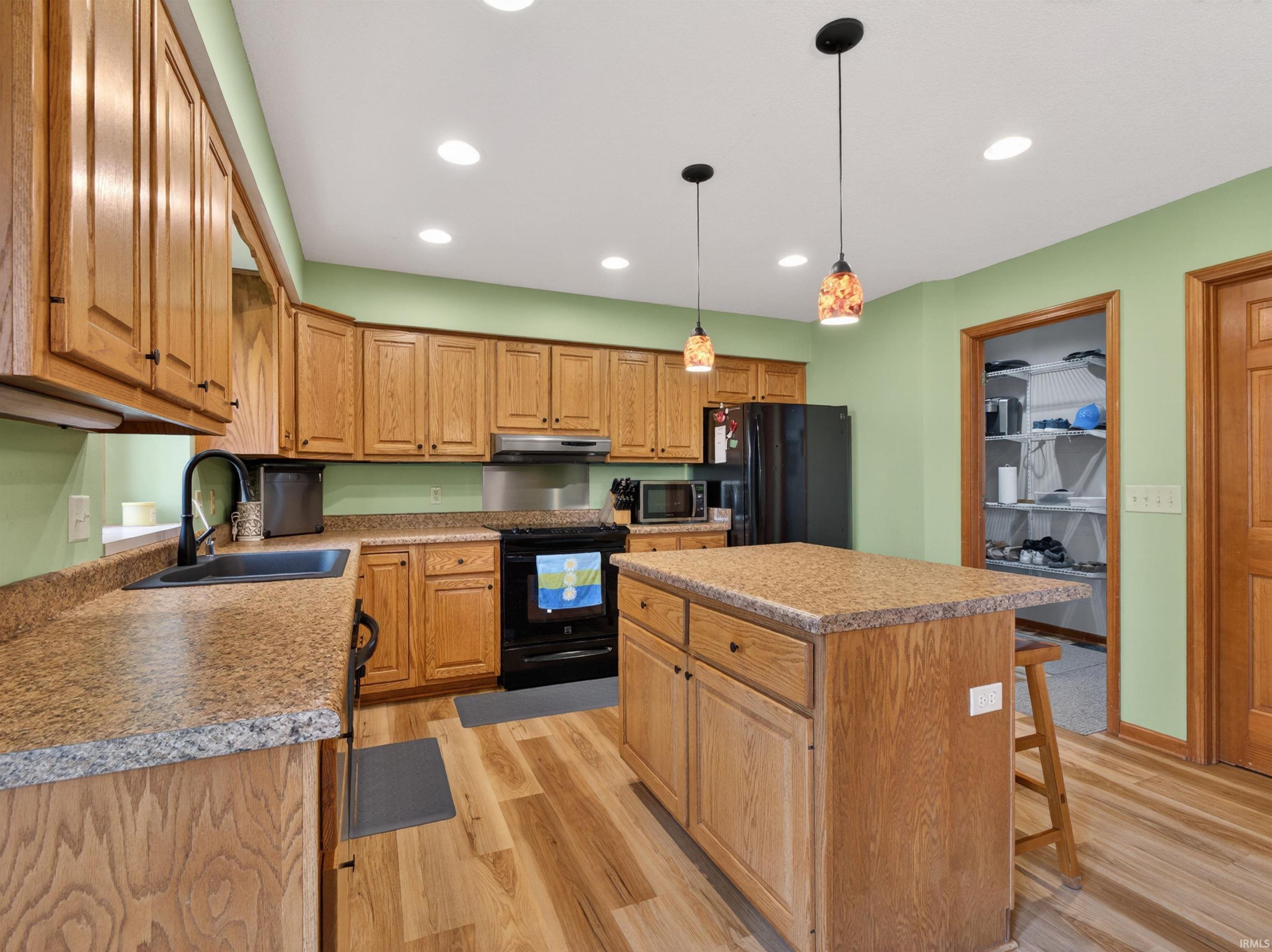 Kitchen featuring wood-finish cabinetry, granite-look countertops, and wood-finish flooring
