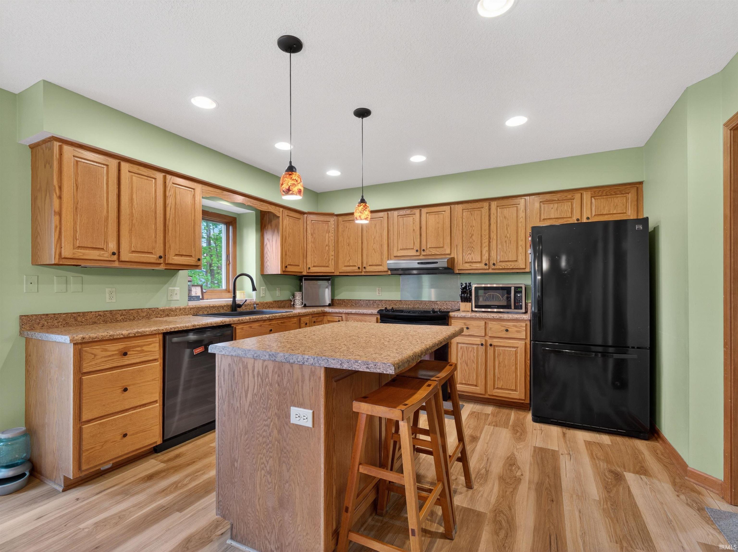Kitchen featuring wood-finish flooring, light wood cabinetry, stone-look countertops, and recessed lighting