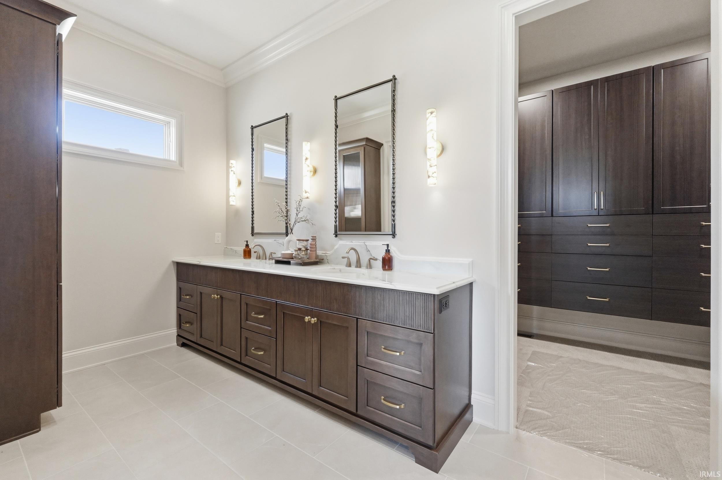 Dual vanity featuring dark wood-finish cabinetry, white countertop, and individual framed mirrors with sconce lighting