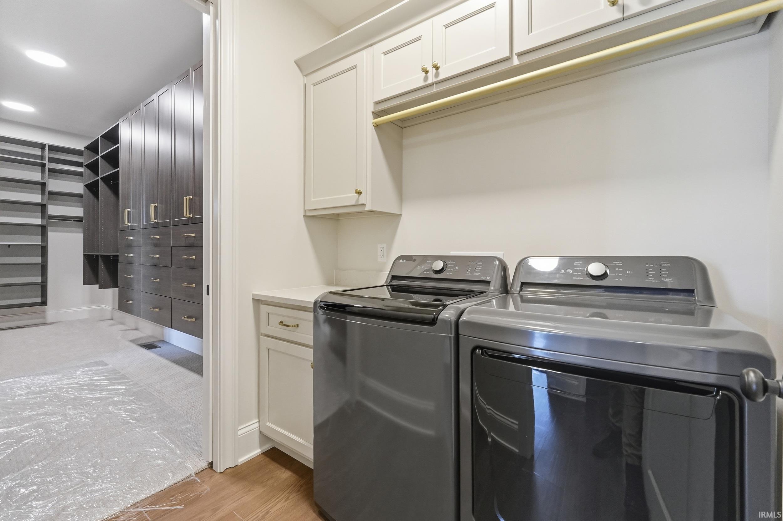 Dedicated laundry area featuring a built-in counter, upper and lower cabinetry with gold-tone hardware, and a hanging rod
