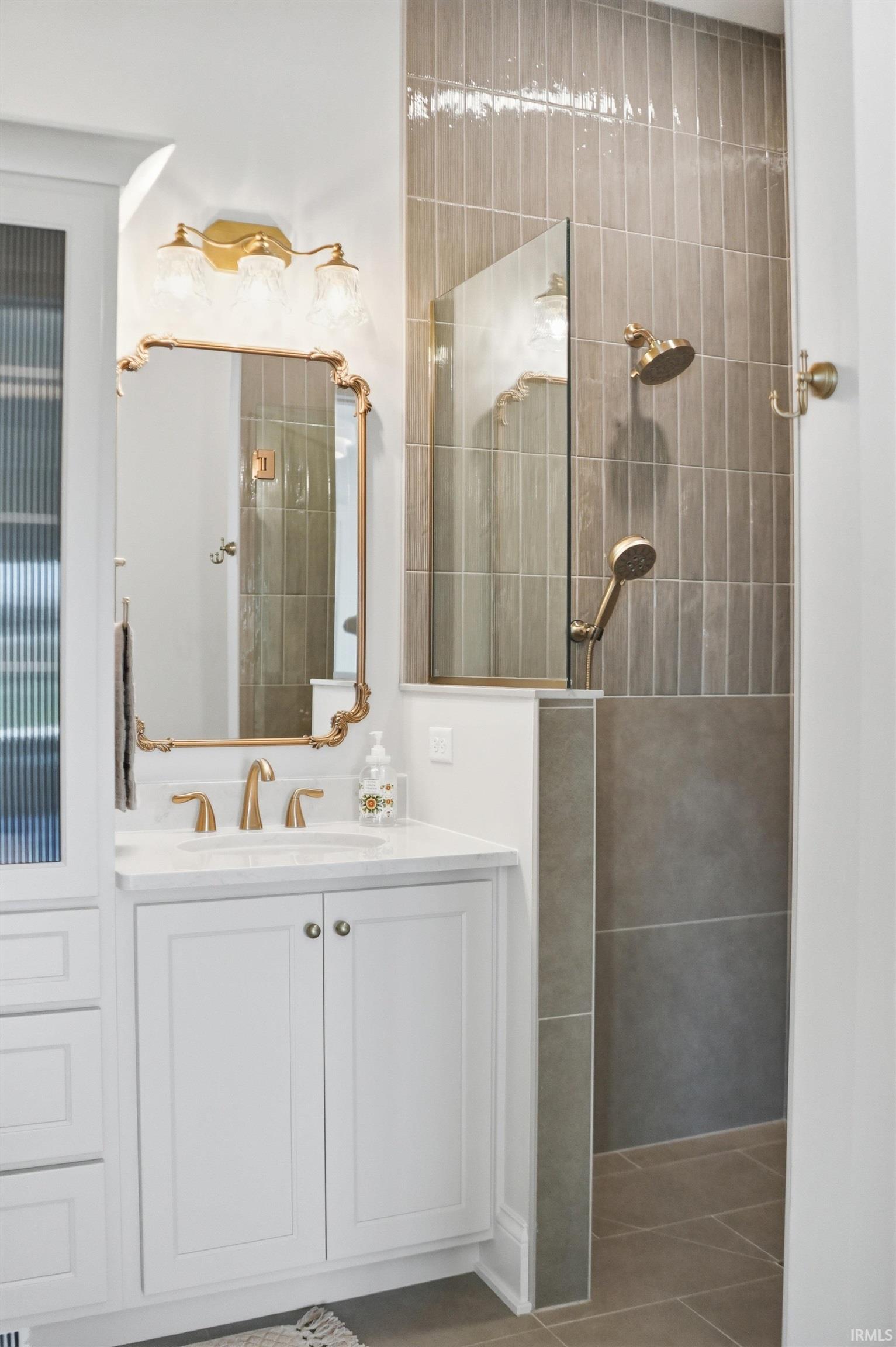 Walk-in shower with a glass panel, two shower heads, and vertical tile