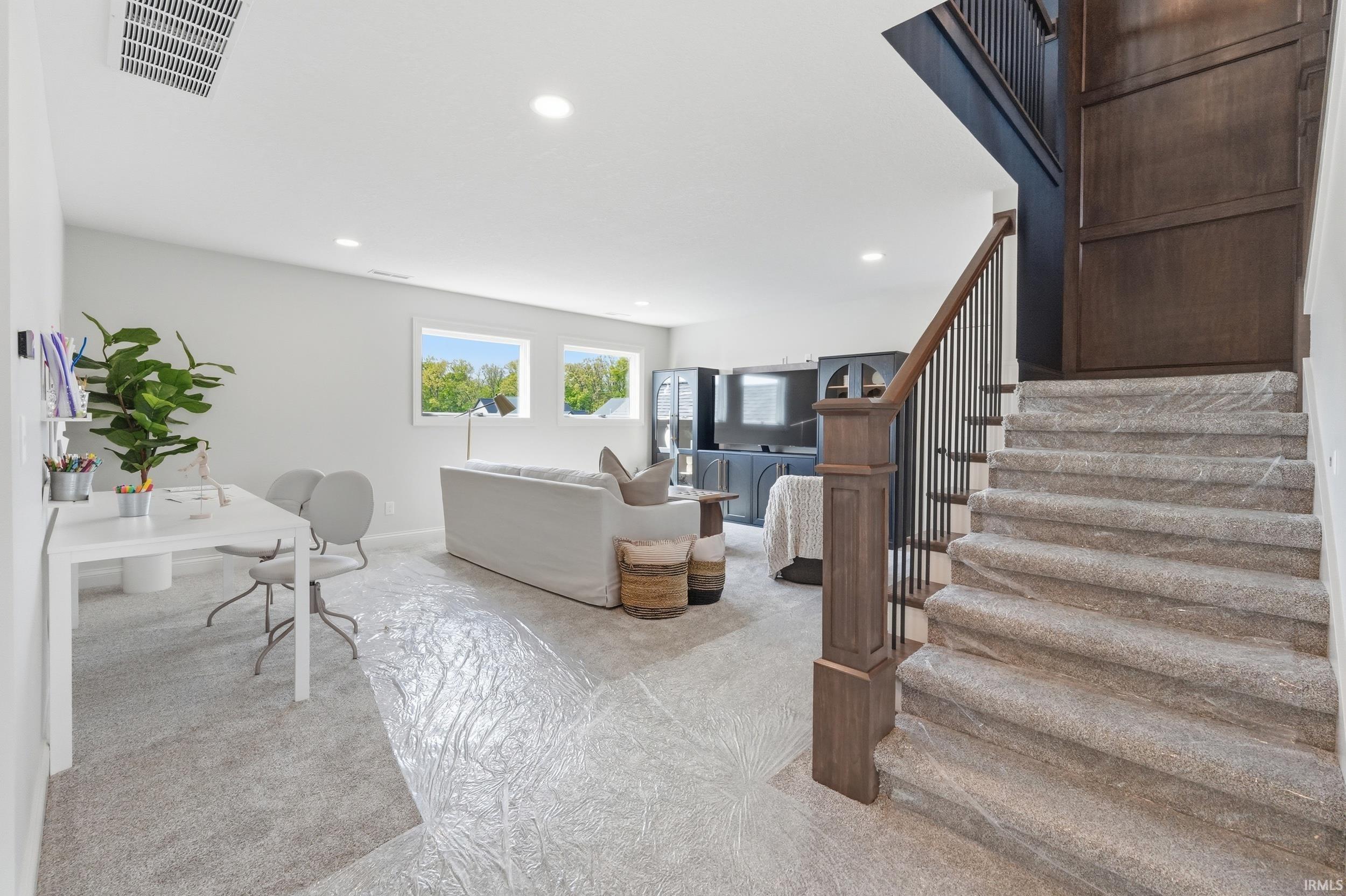 Spacious finished lower level featuring a carpeted staircase with wood newel posts and metal spindles