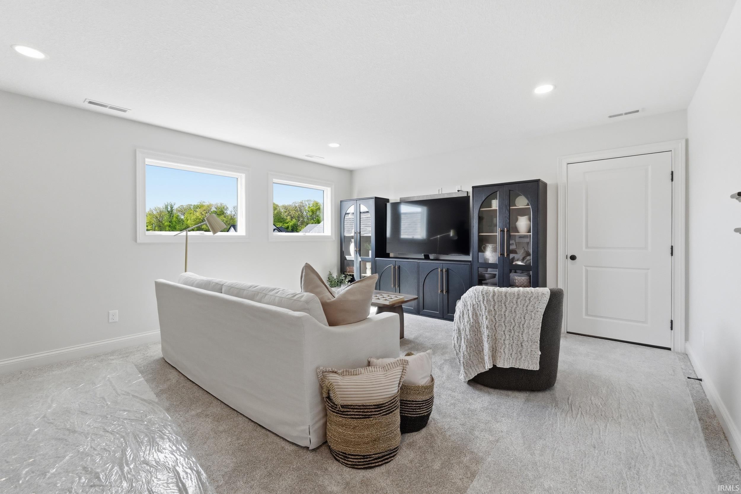 Spacious room featuring light-colored carpeting, recessed lighting, and white baseboards