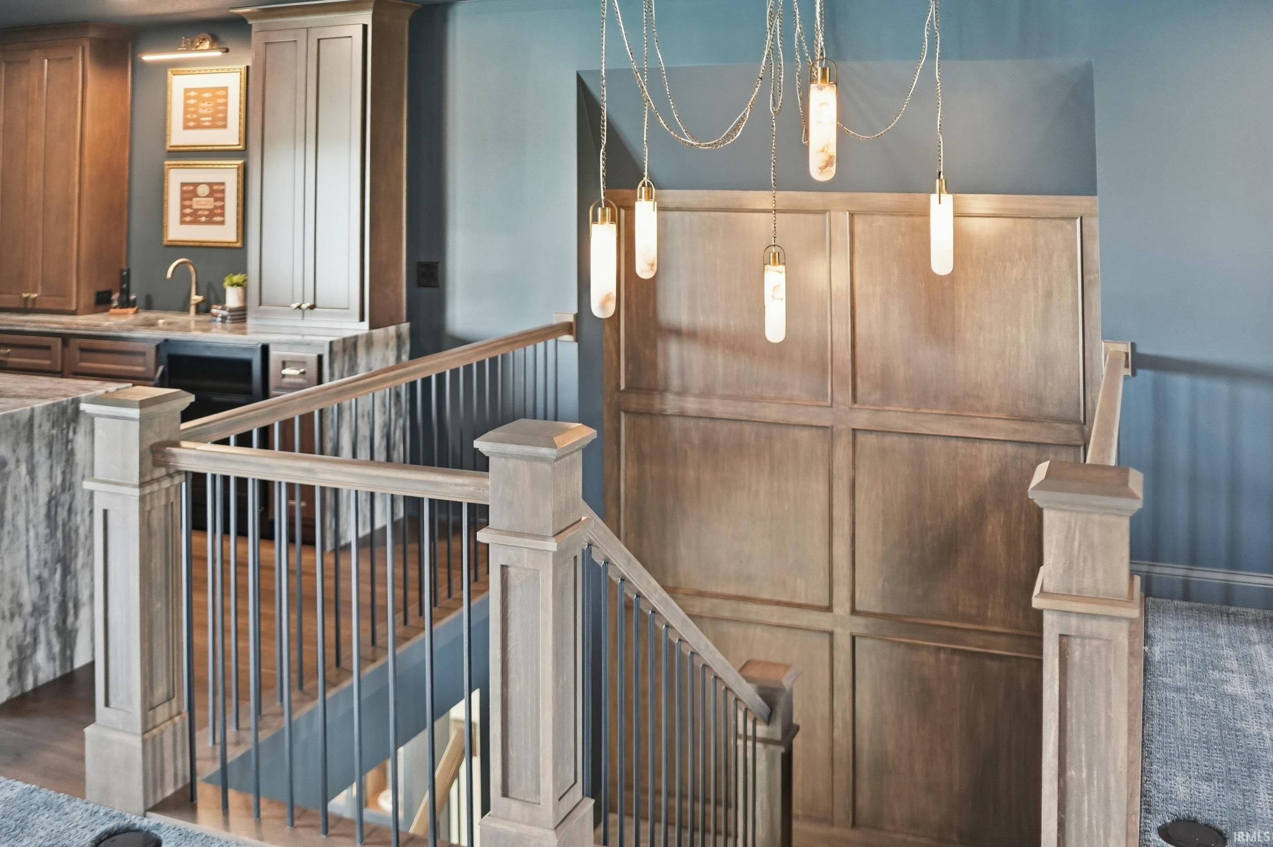Staircase featuring wood-finish newel posts and handrails with black iron balusters