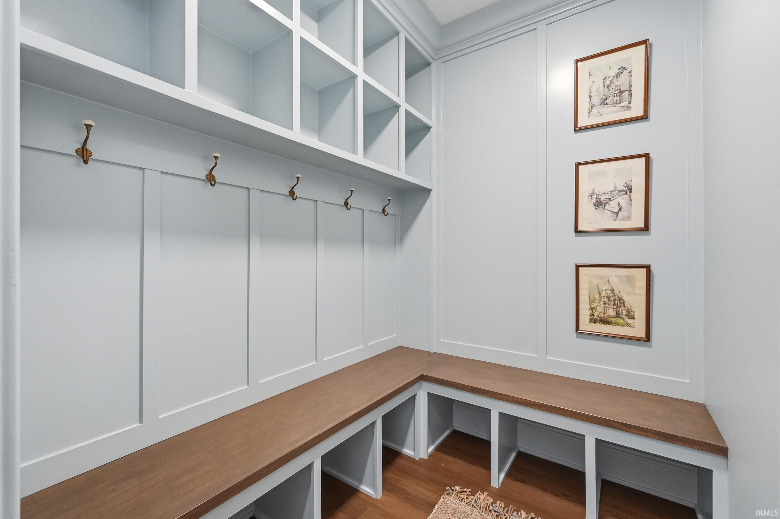 Built-in mudroom features custom cabinetry, an L-shaped bench with wood-finish tops, integrated cubbies, and overhead storage compartments