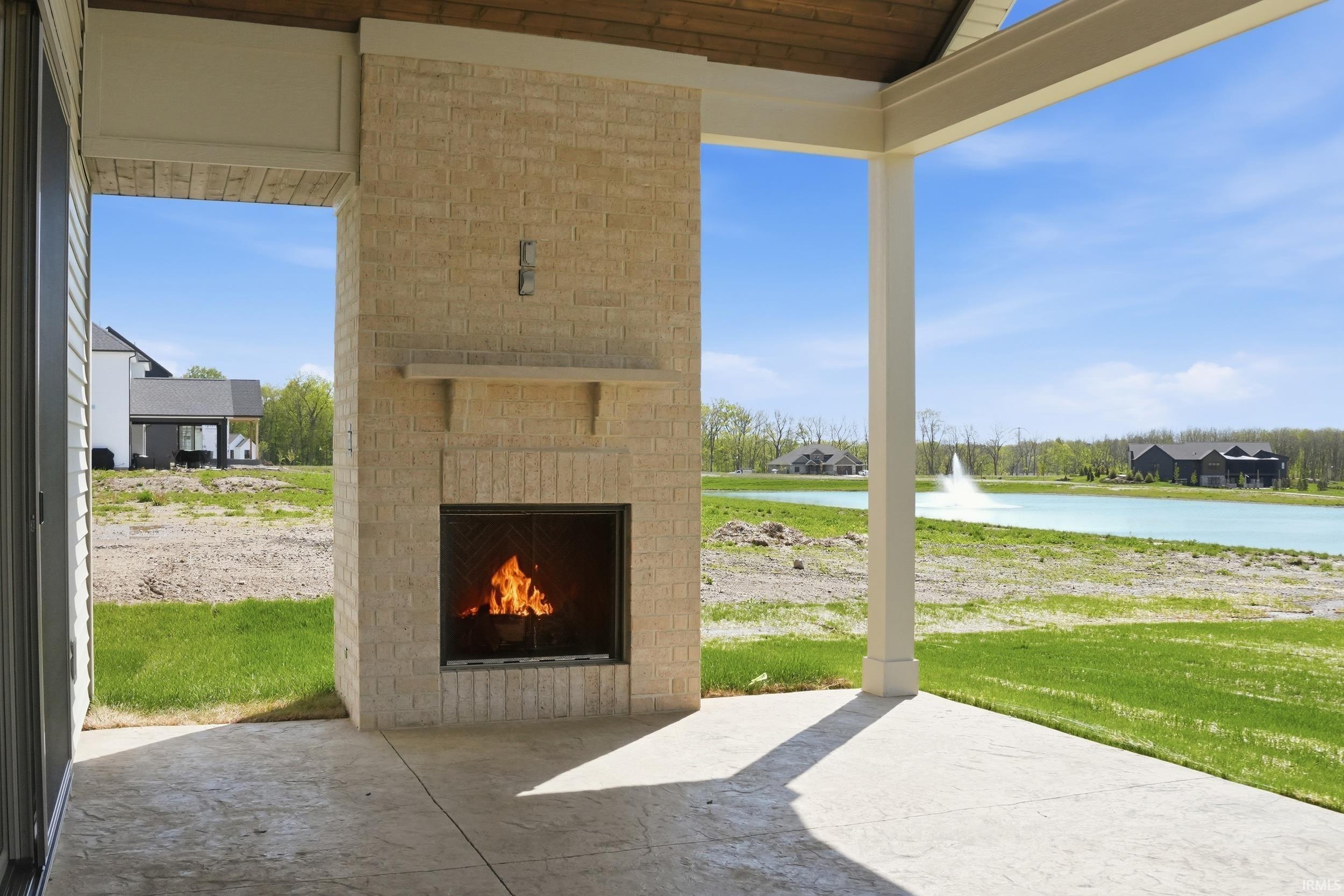 Covered patio featuring a brick fireplace with a stone mantel, concrete flooring, and a wood-finish ceiling