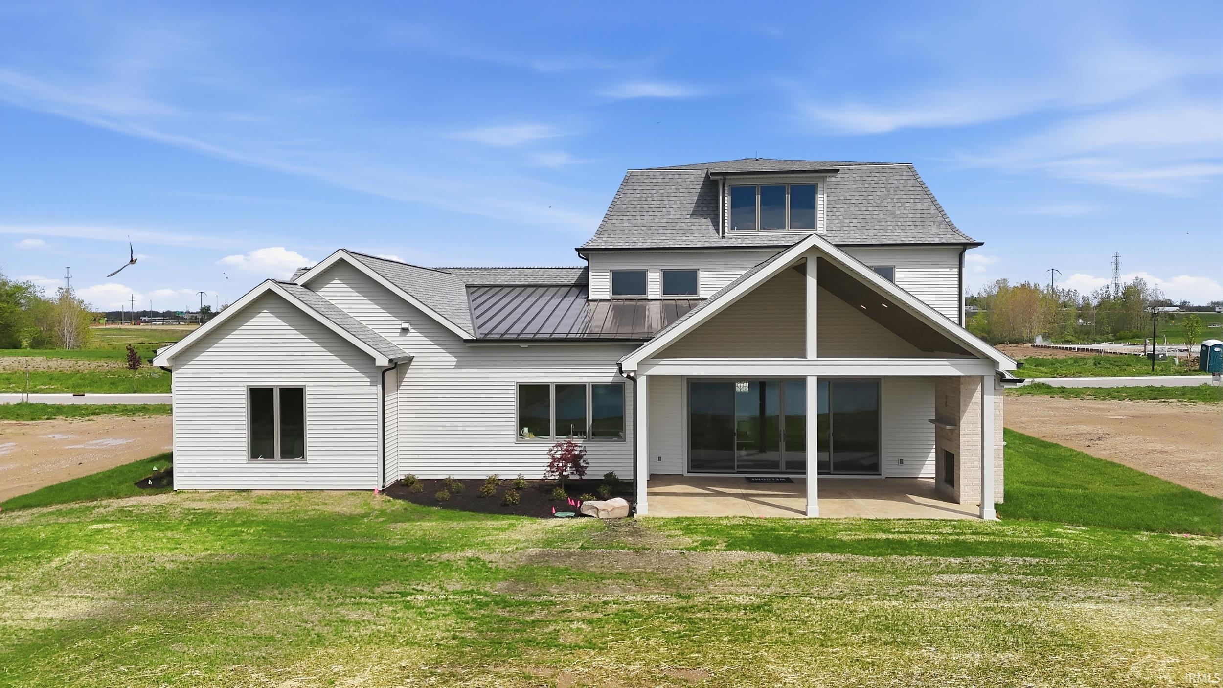 Rear exterior showcasing a covered patio with a built-in outdoor fireplace and sliding glass doors