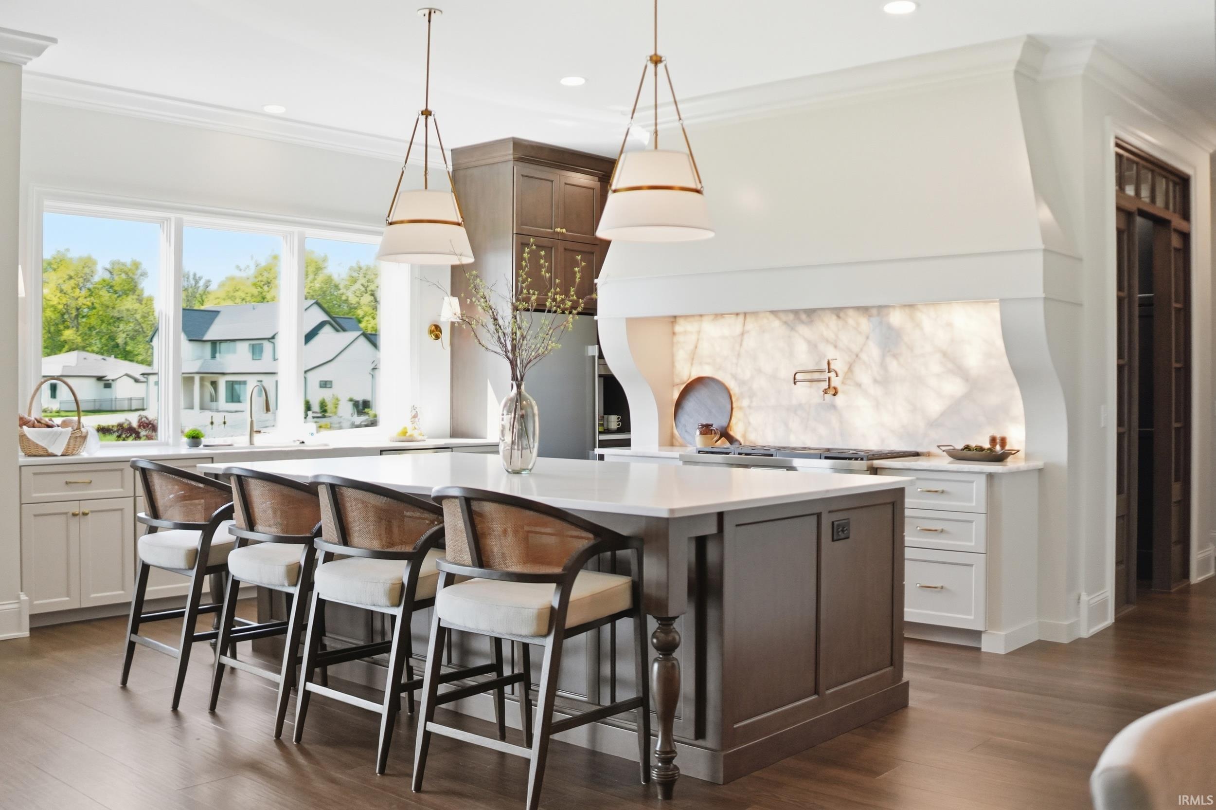 Gourmet kitchen featuring a large central island with seating, a built-in cooktop, a backlit stone backsplash, custom cabinetry, and wood-finish flooring
