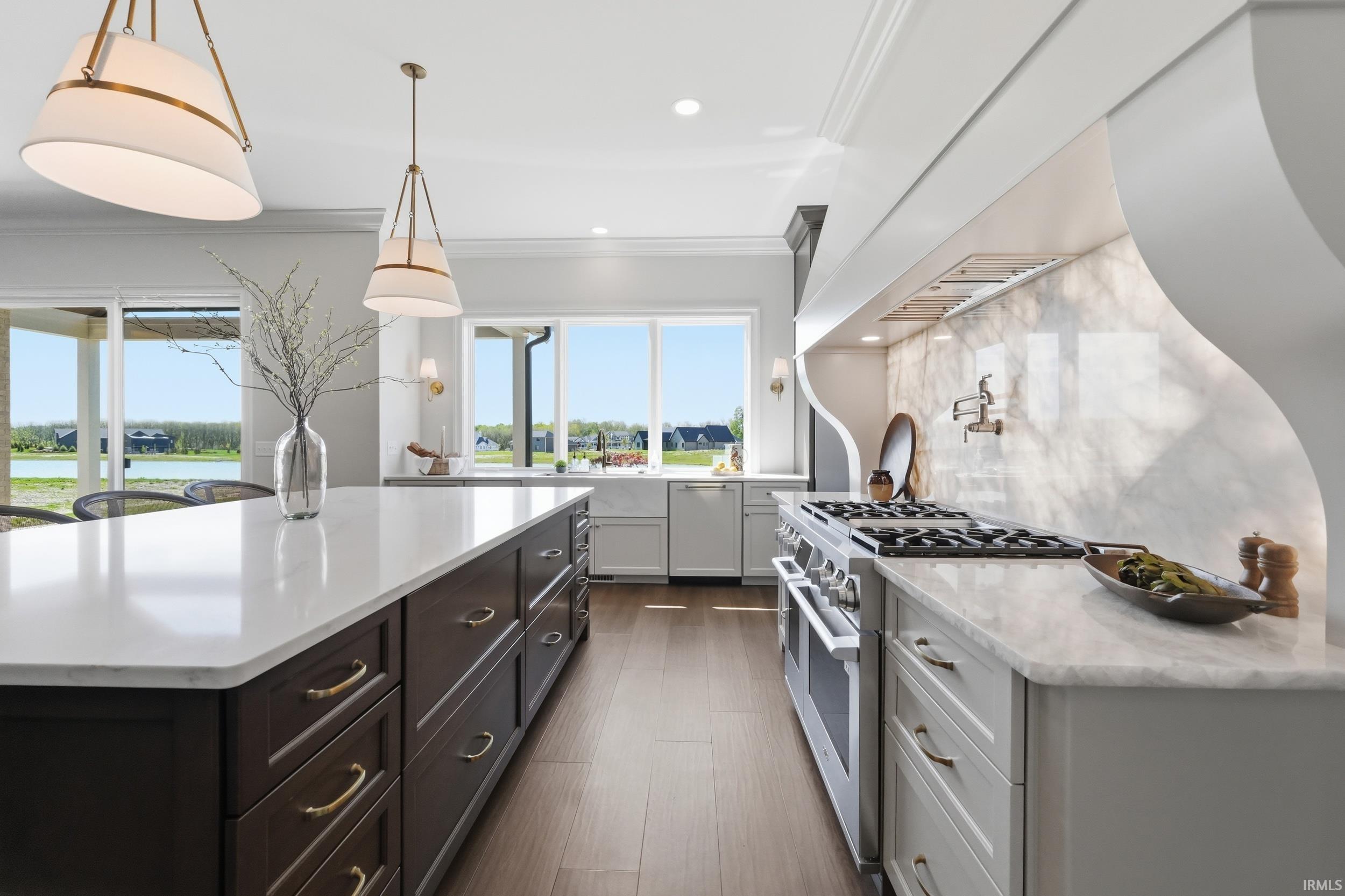 Gourmet kitchen featuring a large central island with a solid surface countertop, a professional-grade range, a tile backsplash, and a wall-mounted pot filler