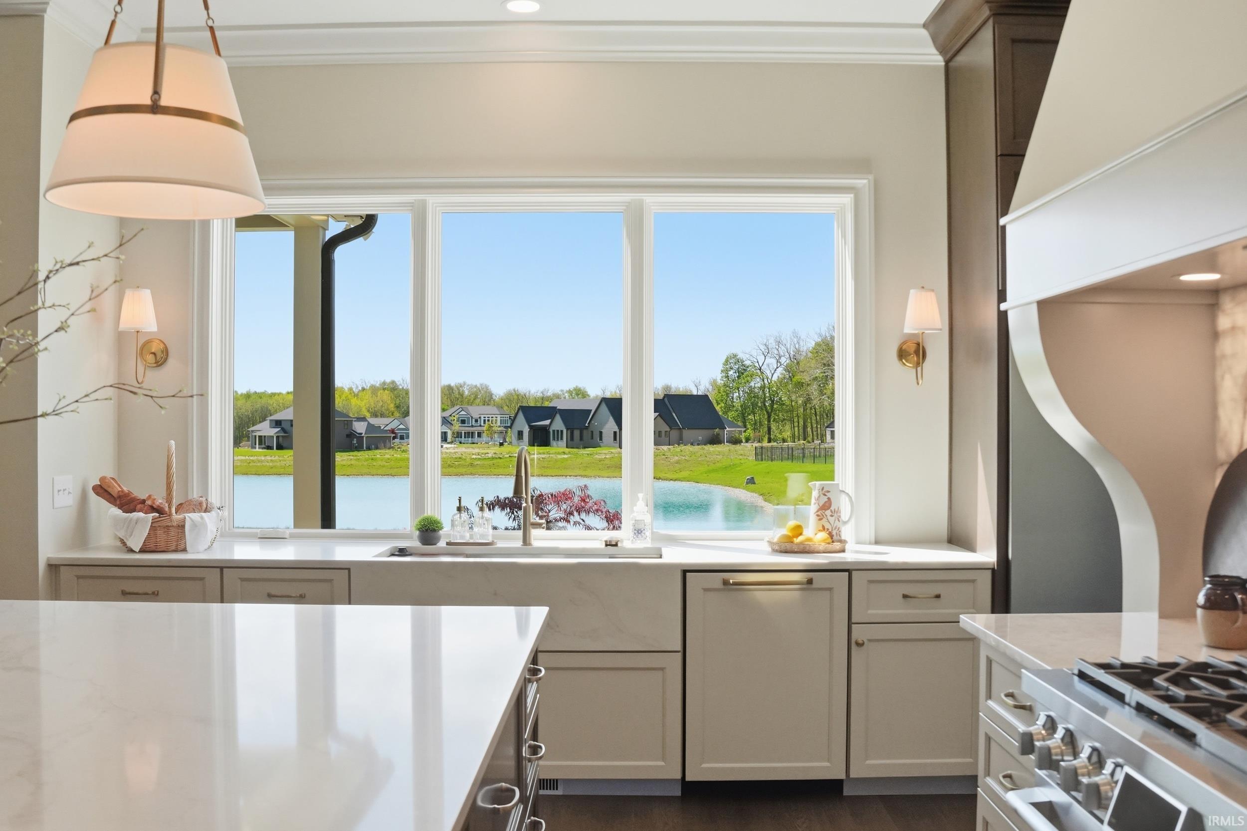 Kitchen featuring a large window overlooking a body of water, built-in dishwasher, deep farmhouse sink, recessed lighting, and wall sconces