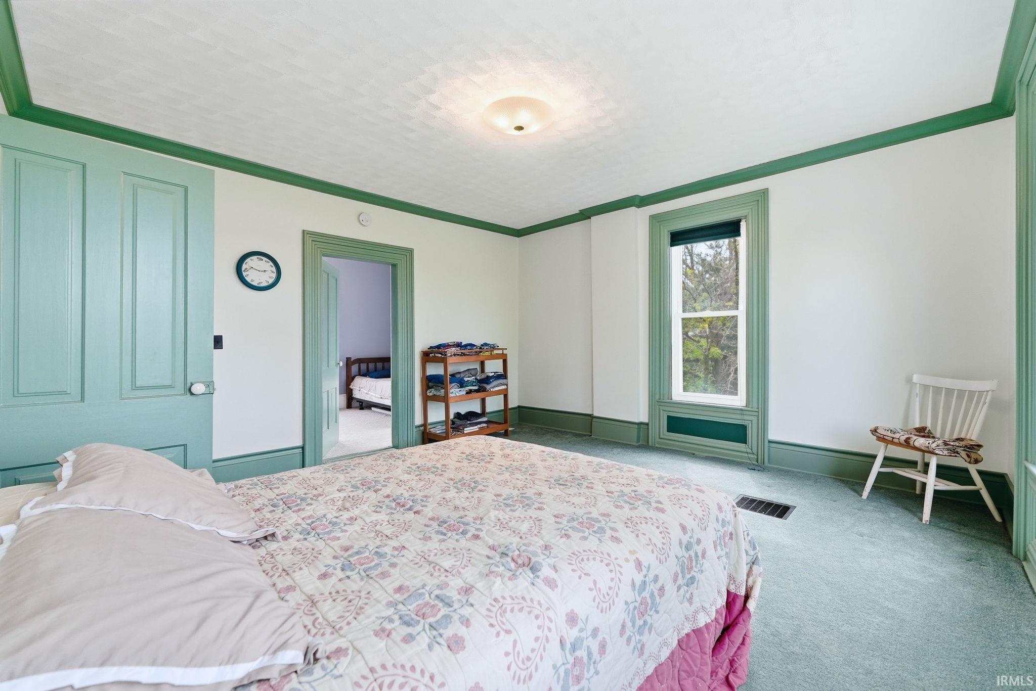 Bedroom featuring light green carpeting, white walls, and green trim details