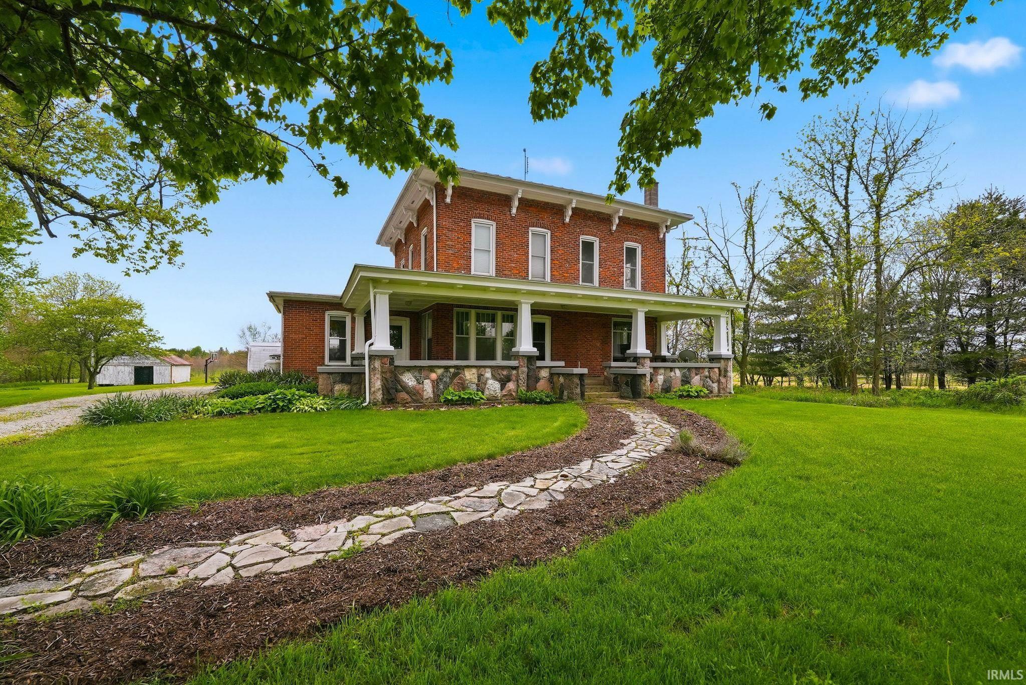 Brick residence featuring a full-width covered porch with stone pillars