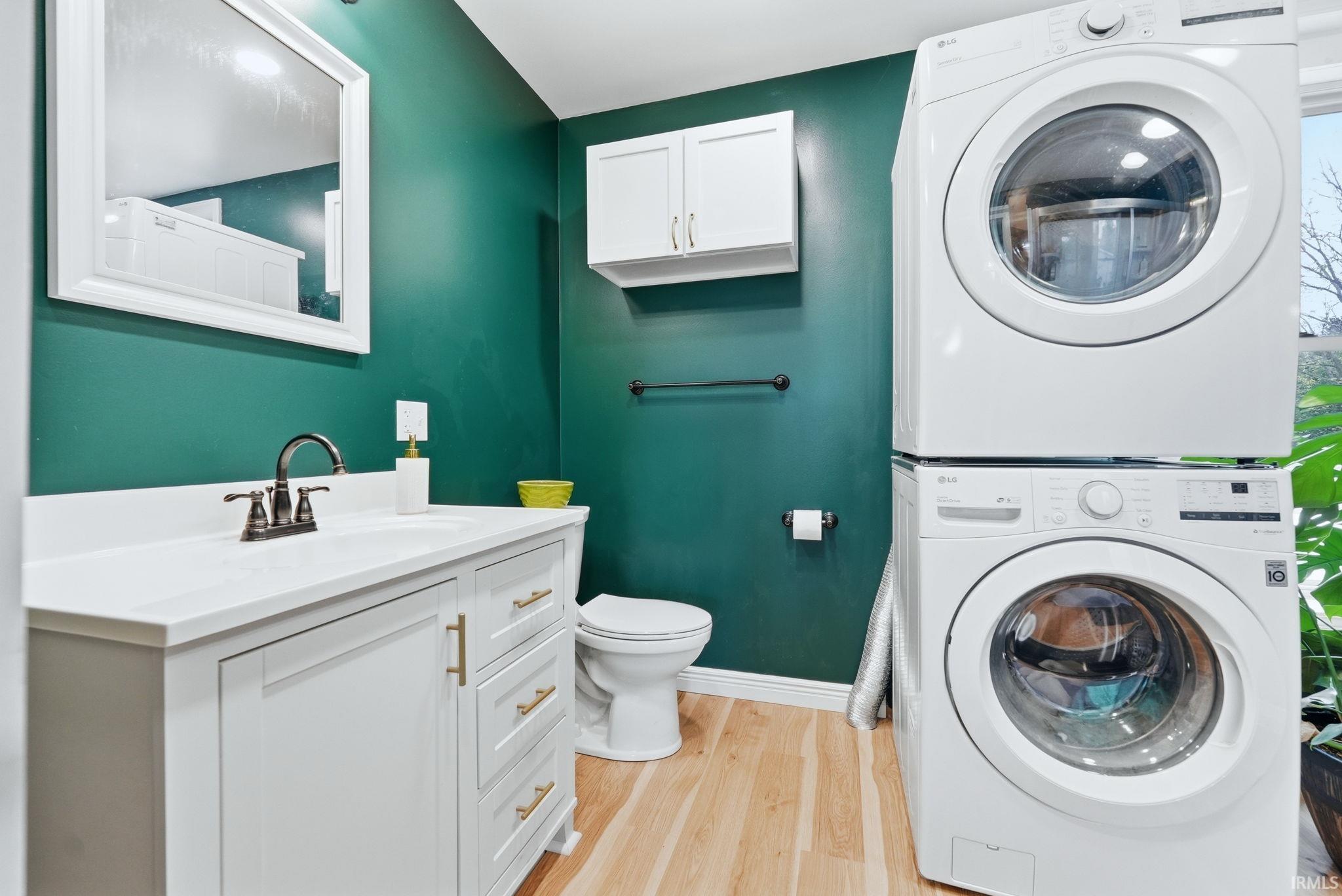 Full bathroom featuring a single vanity with brass hardware, a framed mirror, and a toilet
