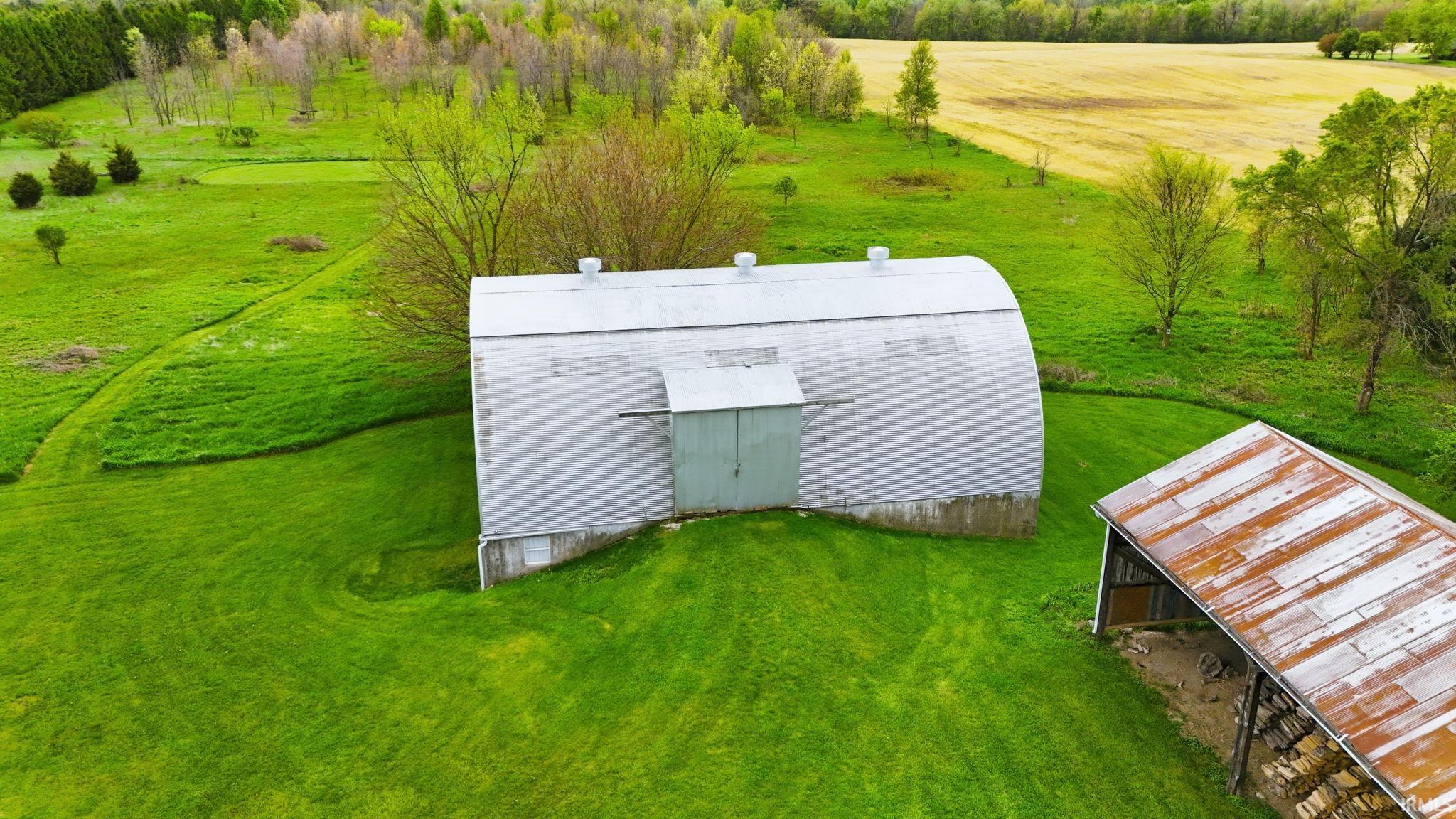 Quonset hut style structure with a corrugated metal roof and siding, complemented by a smaller open-sided barn with a weathered metal roof