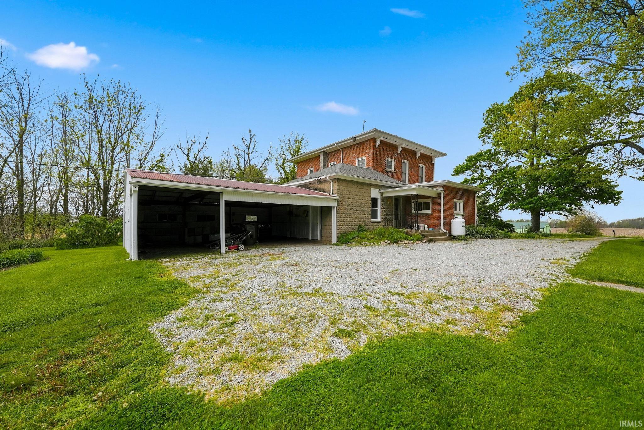 Traditional brick and stone residence featuring a covered front porch and a multi-bay carport