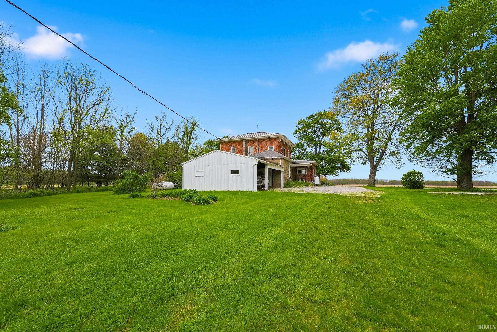 Expansive green lawn with mature trees and a brick-sided residence