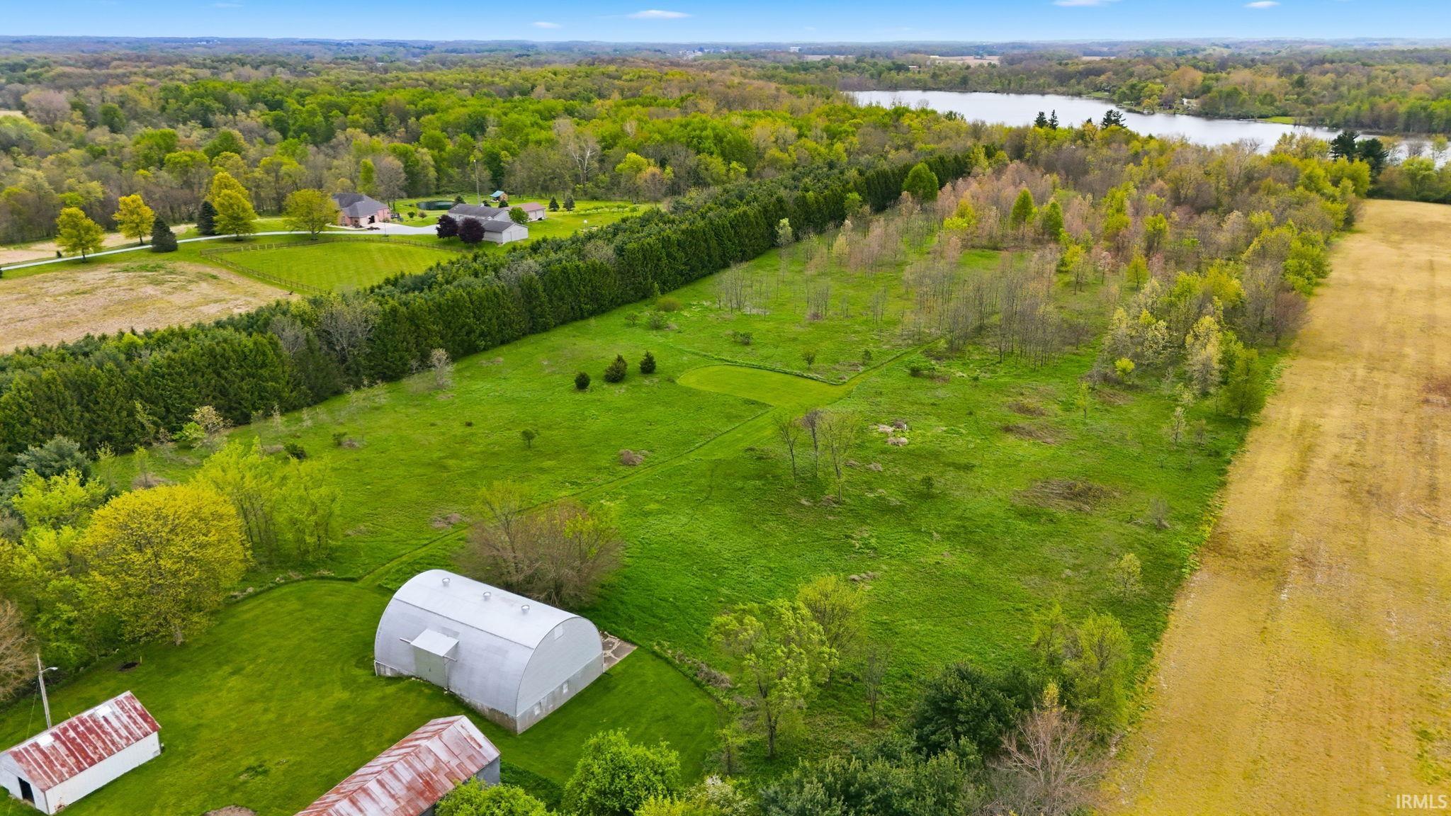 Expansive green landscape featuring a large Quonset hut and multiple outbuildings