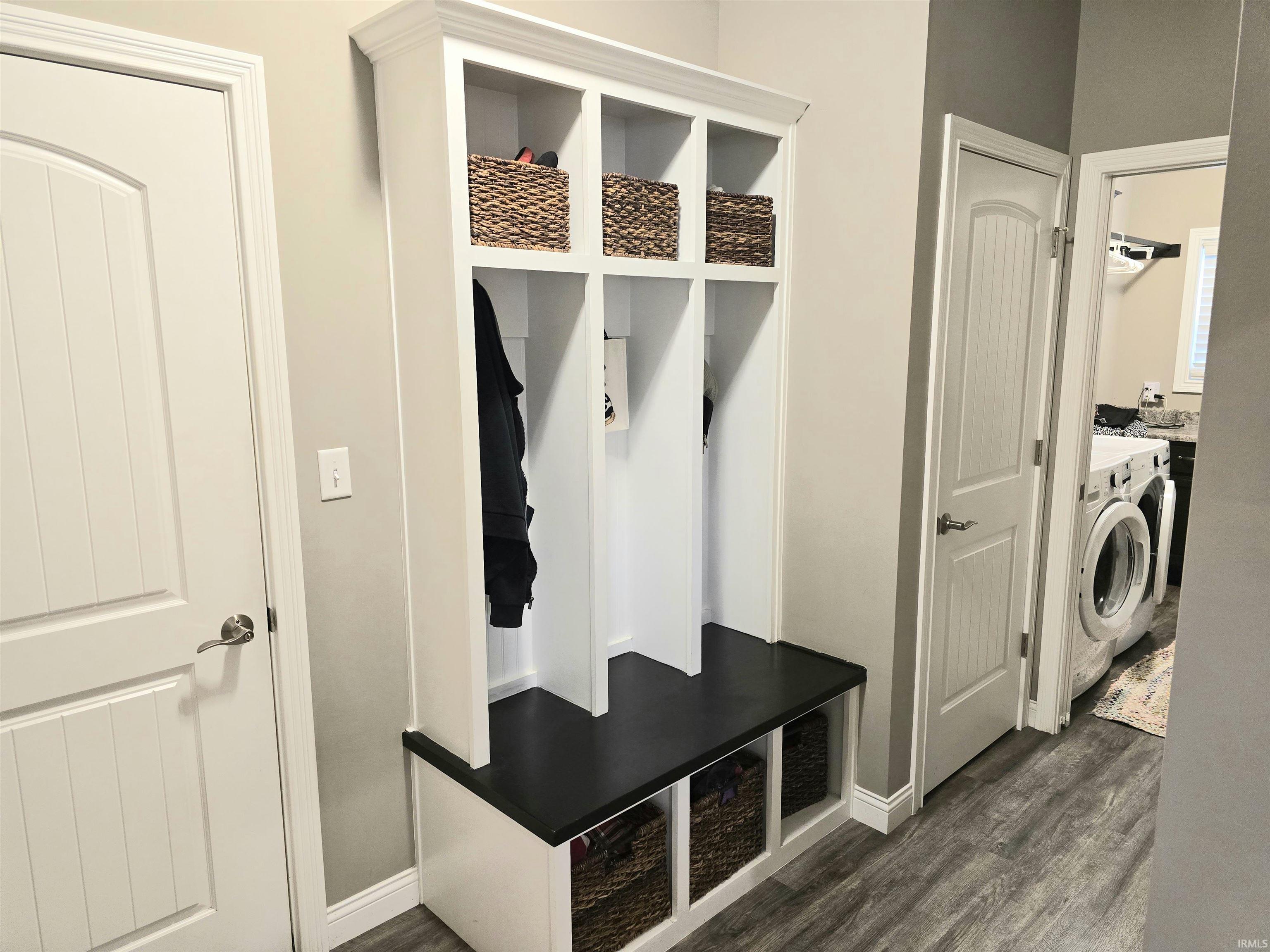 Built-in white storage unit featuring a dark-toned bench, open shelving, and lower cubbies