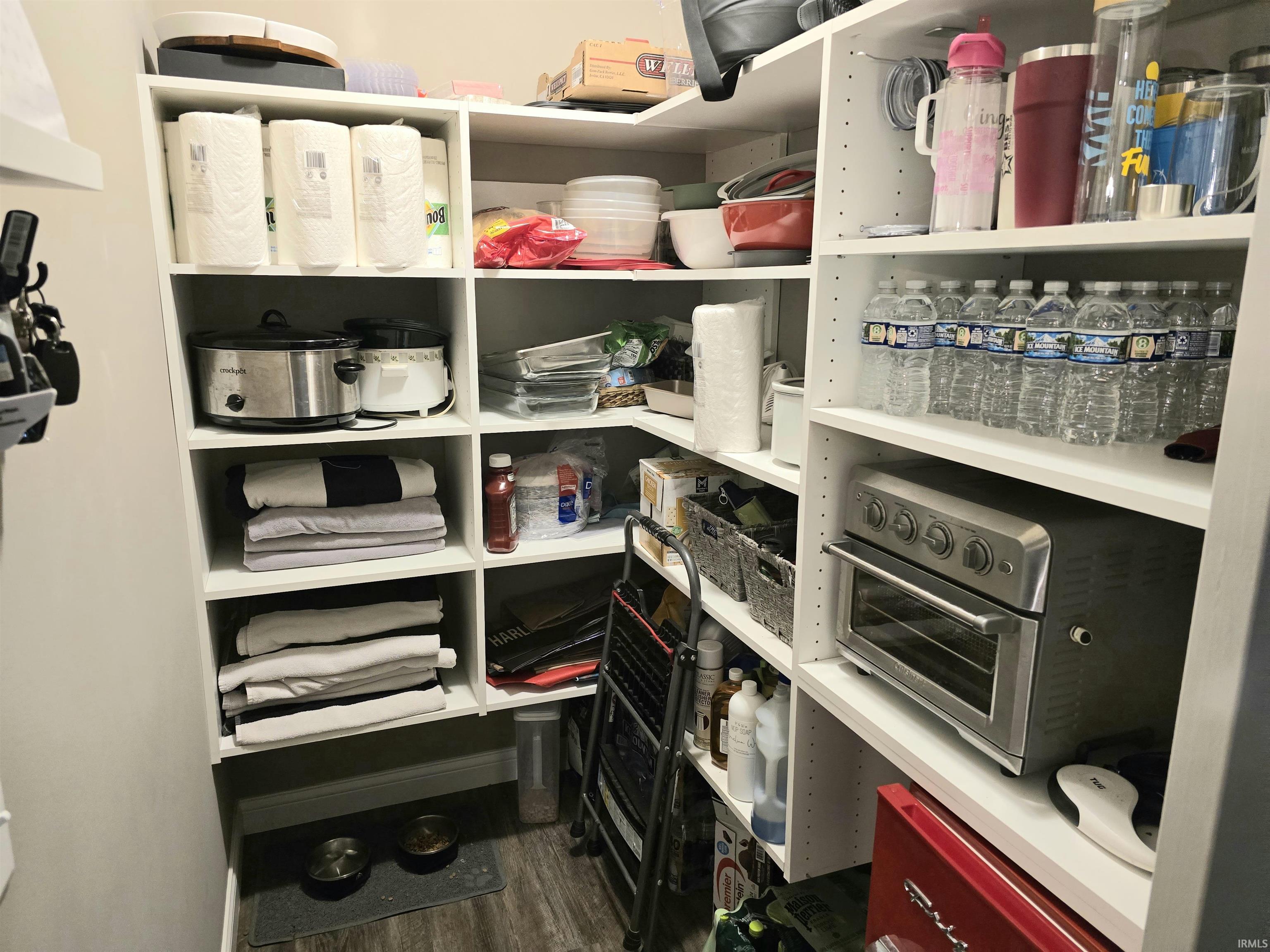 Custom-built pantry featuring white shelving, LVP  flooring, and ample storage compartments