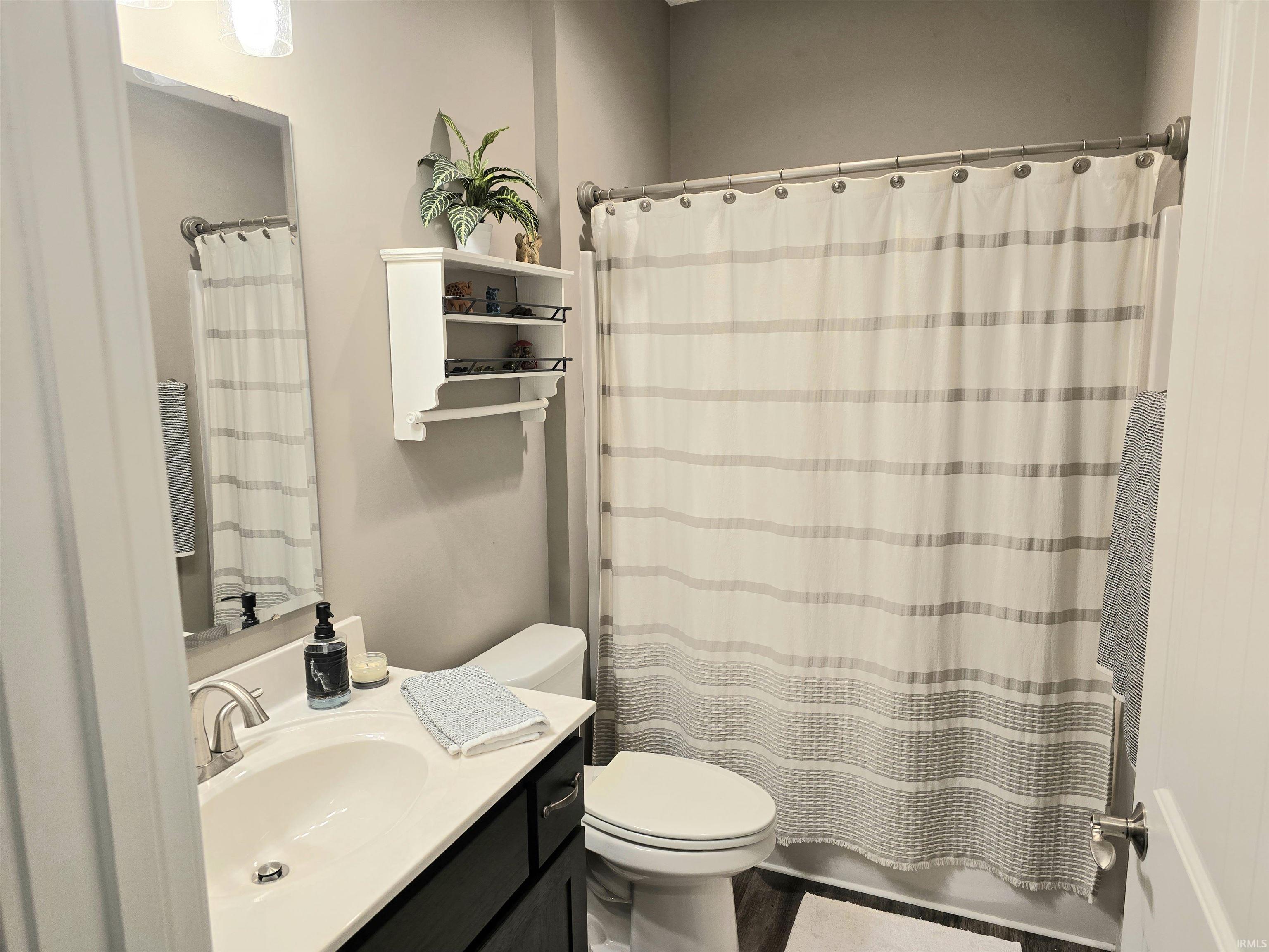 Bathroom featuring a dark wood-finish vanity with an integrated sink, brushed nickel faucet, and a wall-mounted mirror