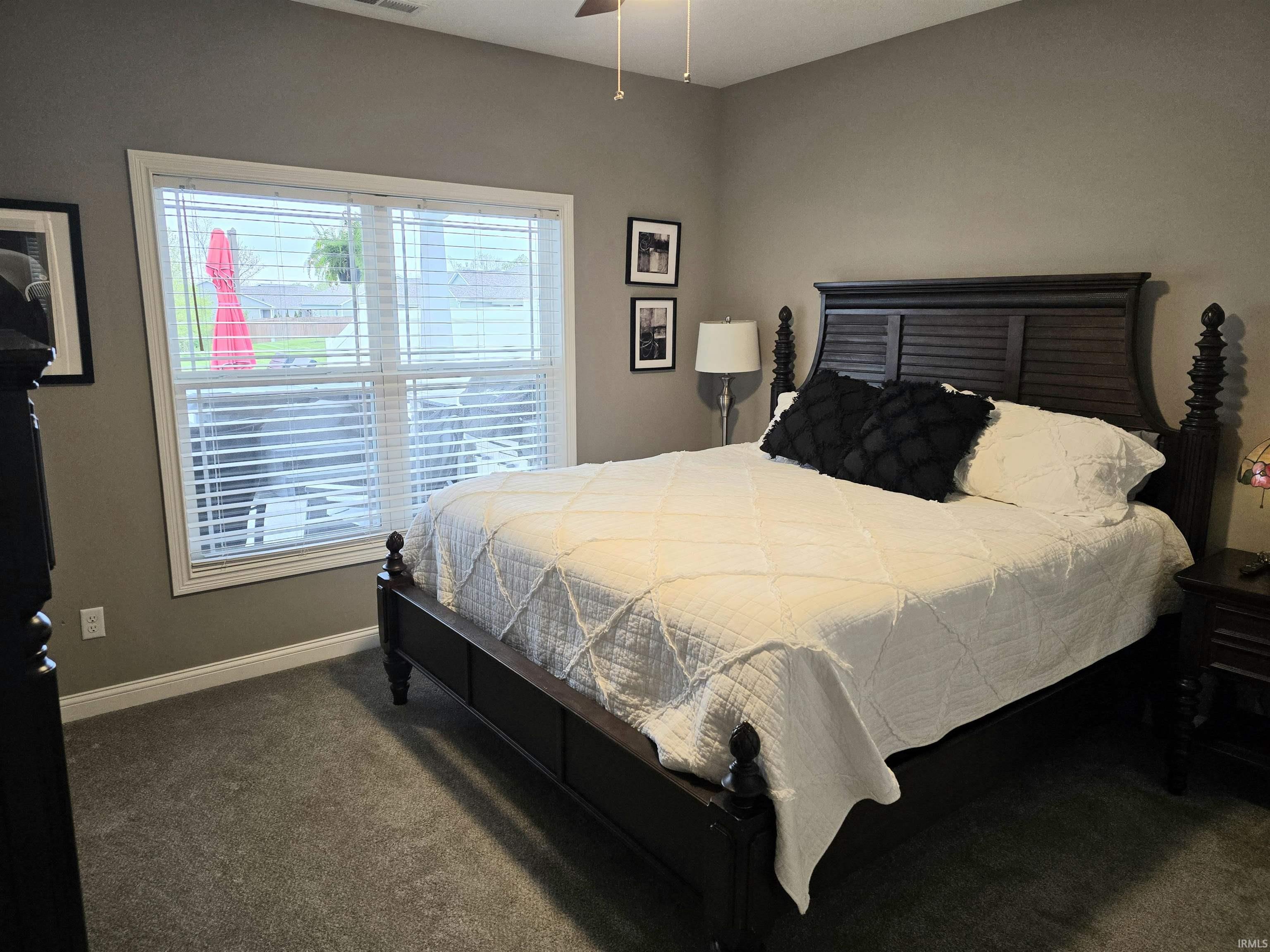 Spacious room featuring neutral painted walls, durable gray carpet flooring, and a large double window with blinds