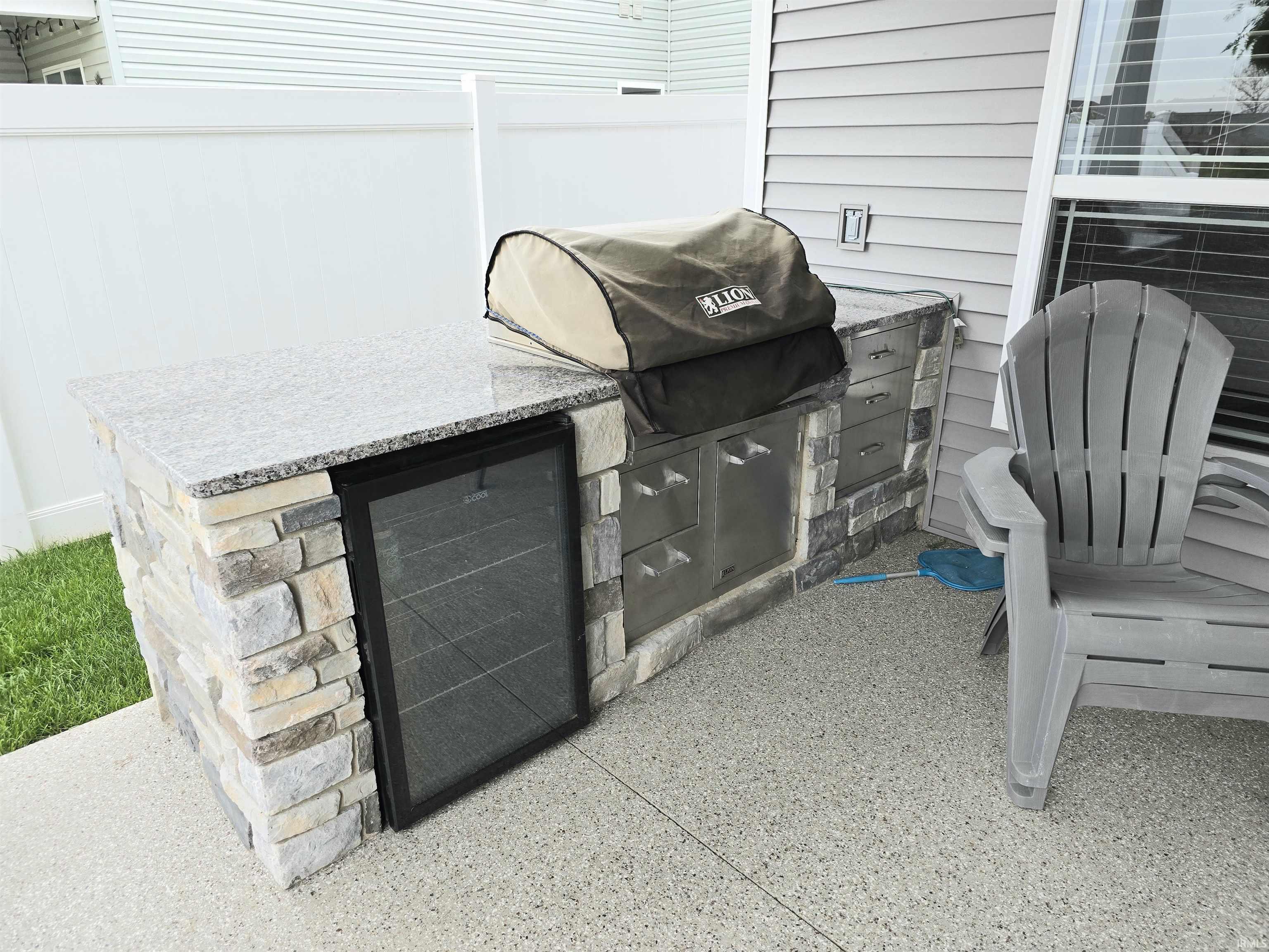 Outdoor kitchen featuring a stone-clad base, integrated stainless steel cabinetry, and a beverage refrigerator