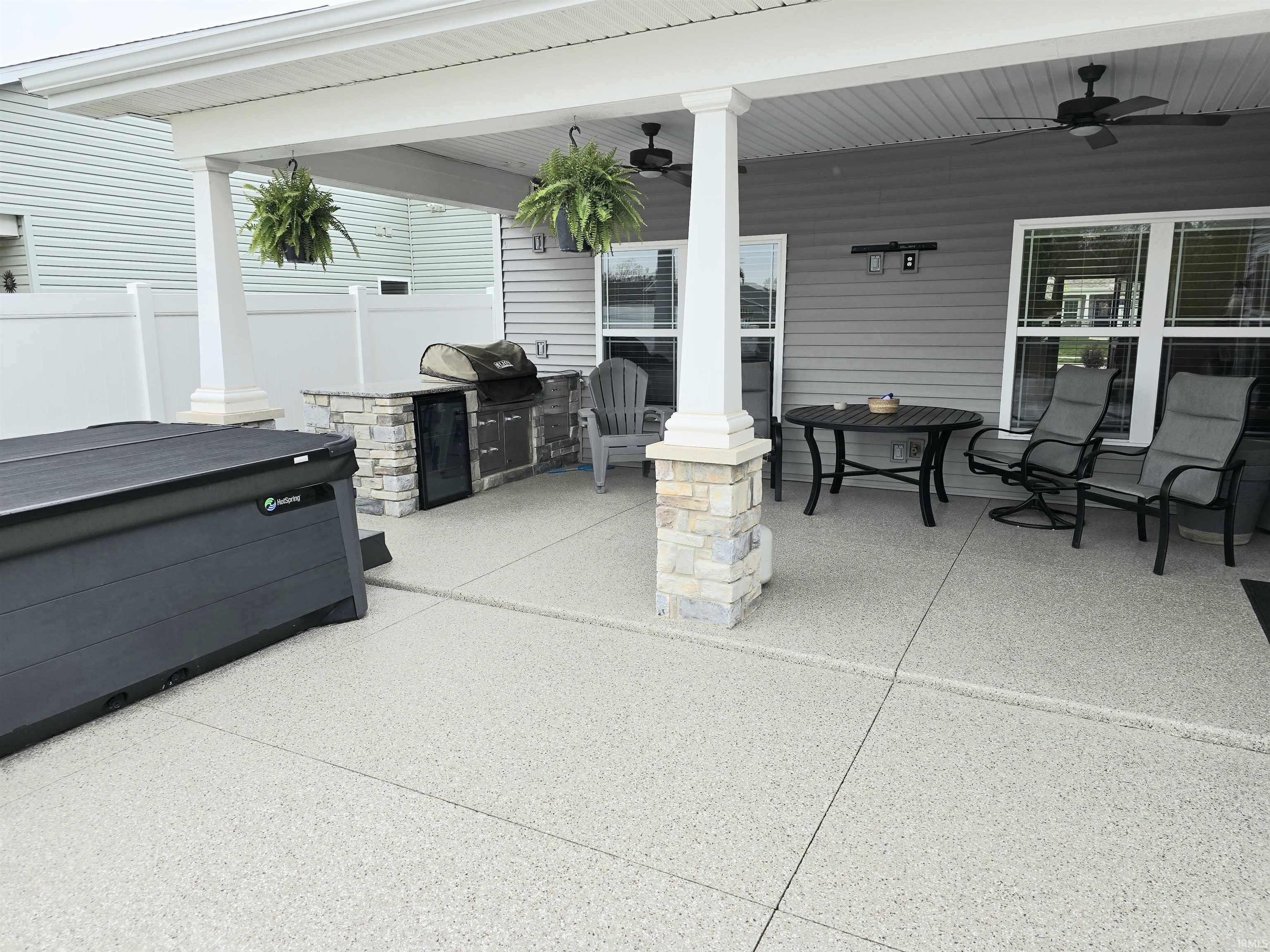 Expansive covered patio featuring a built-in outdoor kitchen, ceiling fans, and epoxy concrete for the entire outside area.