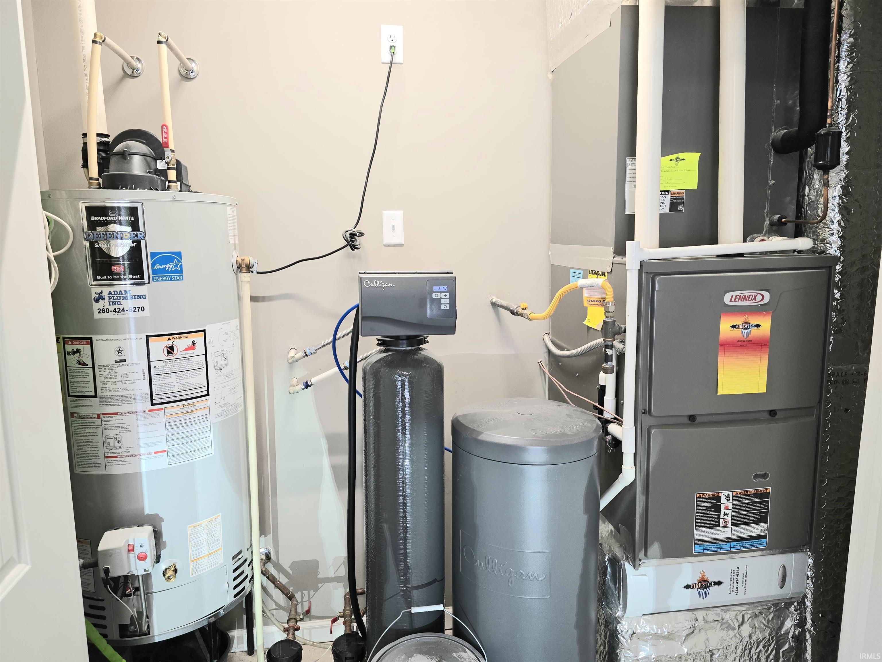 Utility area featuring a water heater, furnace, water softener system, and associated plumbing