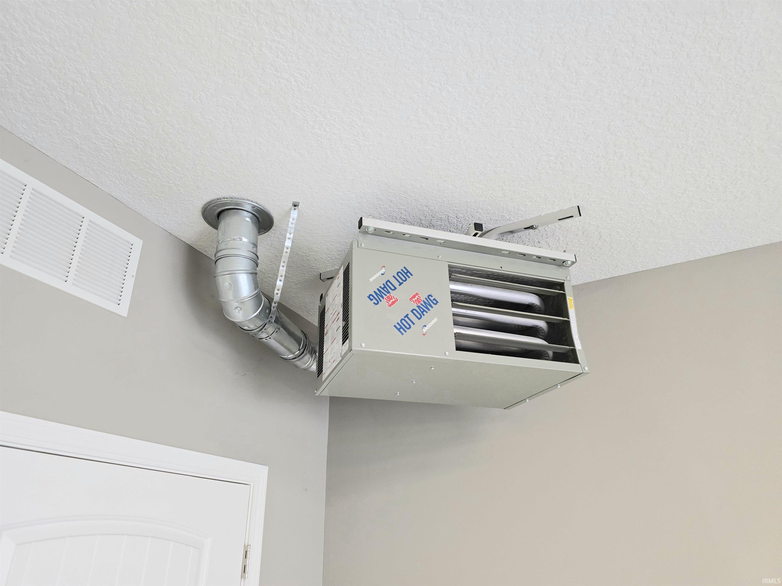 Ceiling-mounted unit heater with visible ductwork and a white ceiling vent