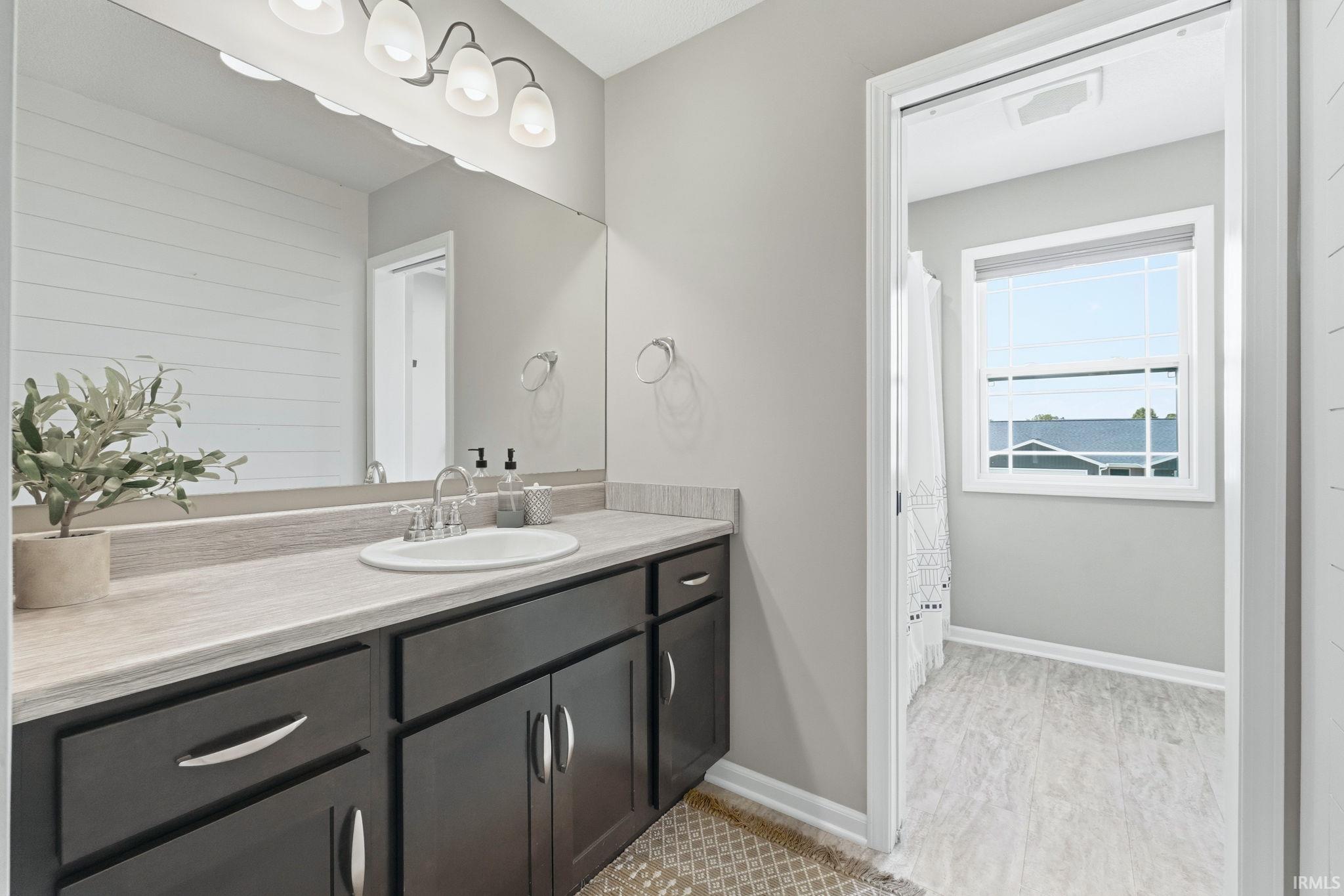 Bathroom featuring a vanity with dark wood-finish cabinetry, a light-toned countertop, and an integrated sink with a chrome faucet