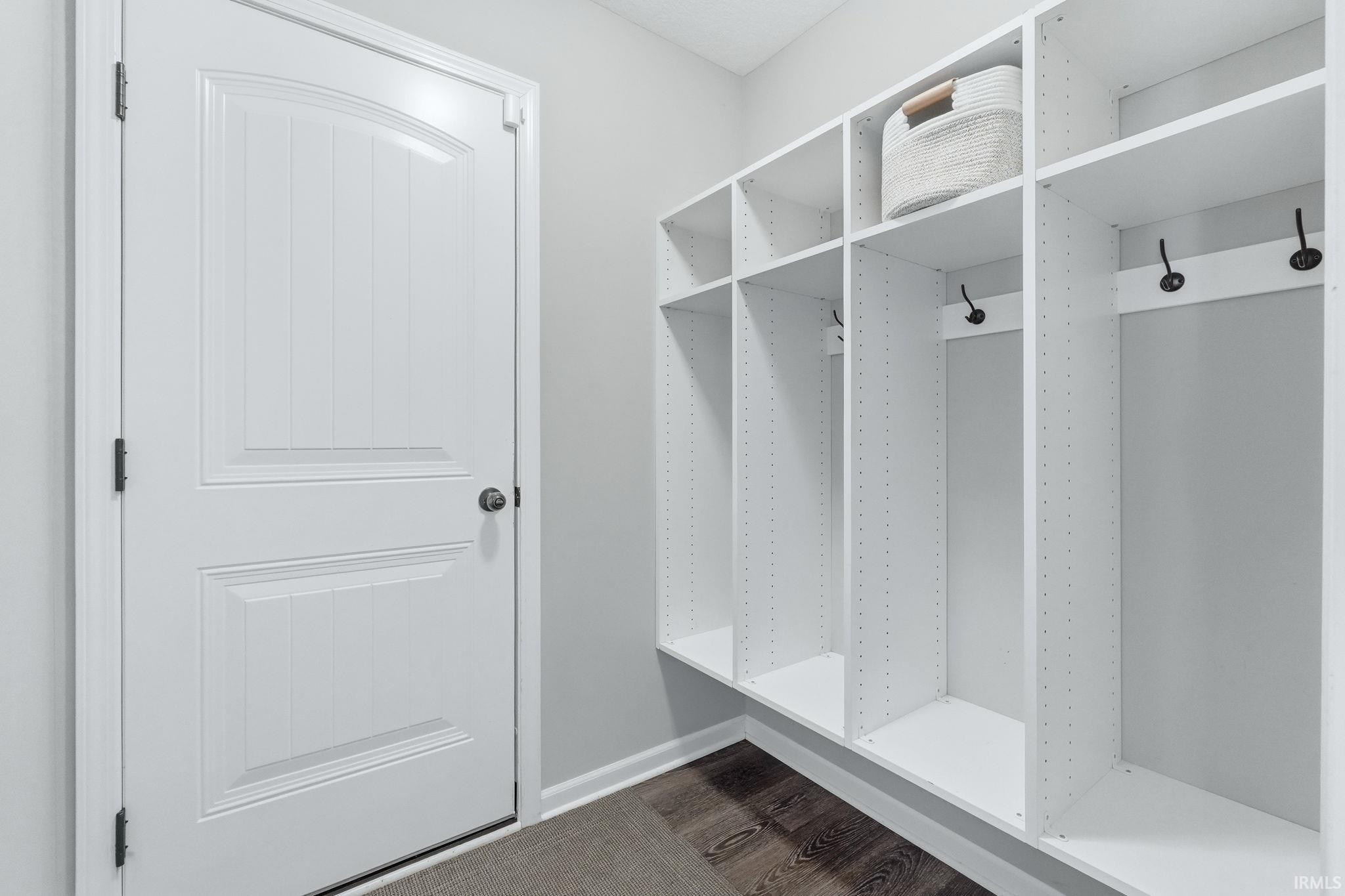 Mudroom featuring white built-in cubbies with integrated hooks, dark wood-finish flooring, and light gray wall paint