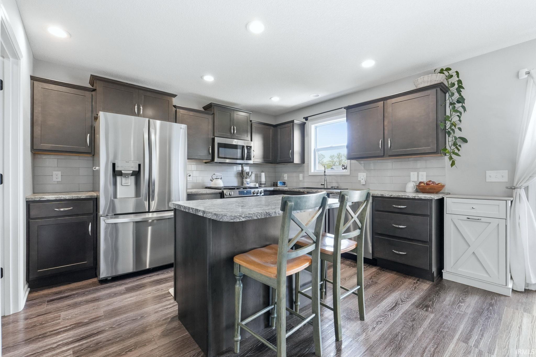 Modern kitchen featuring wood-finish flooring, dark cabinetry, and light countertops
