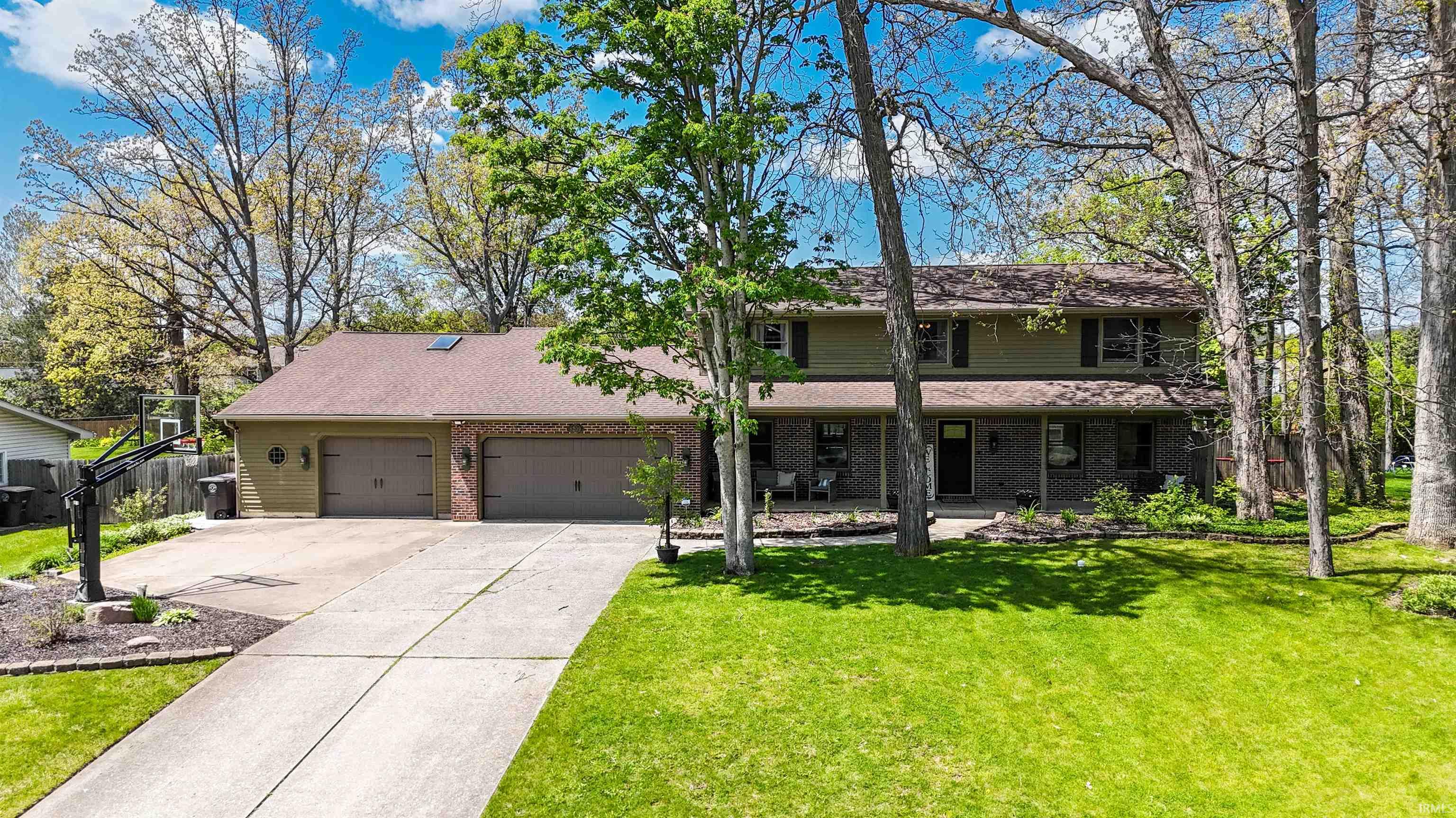 Two-story residence featuring a brick and siding exterior, an attached two-car garage, a covered front porch, and a concrete driveway