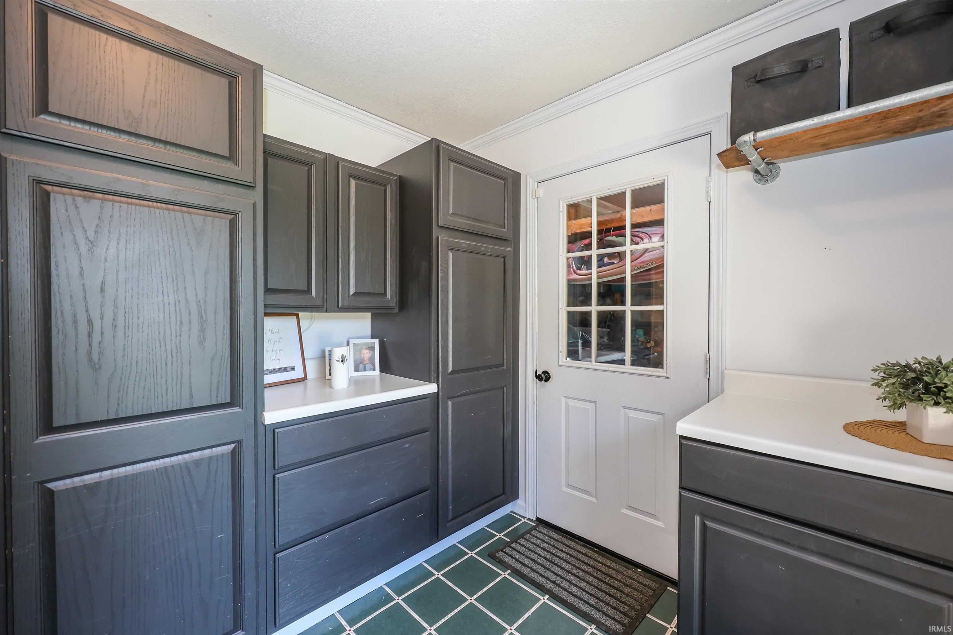 Utility space featuring dark wood-finish cabinetry, white countertops, and a white paneled door with windowpanes