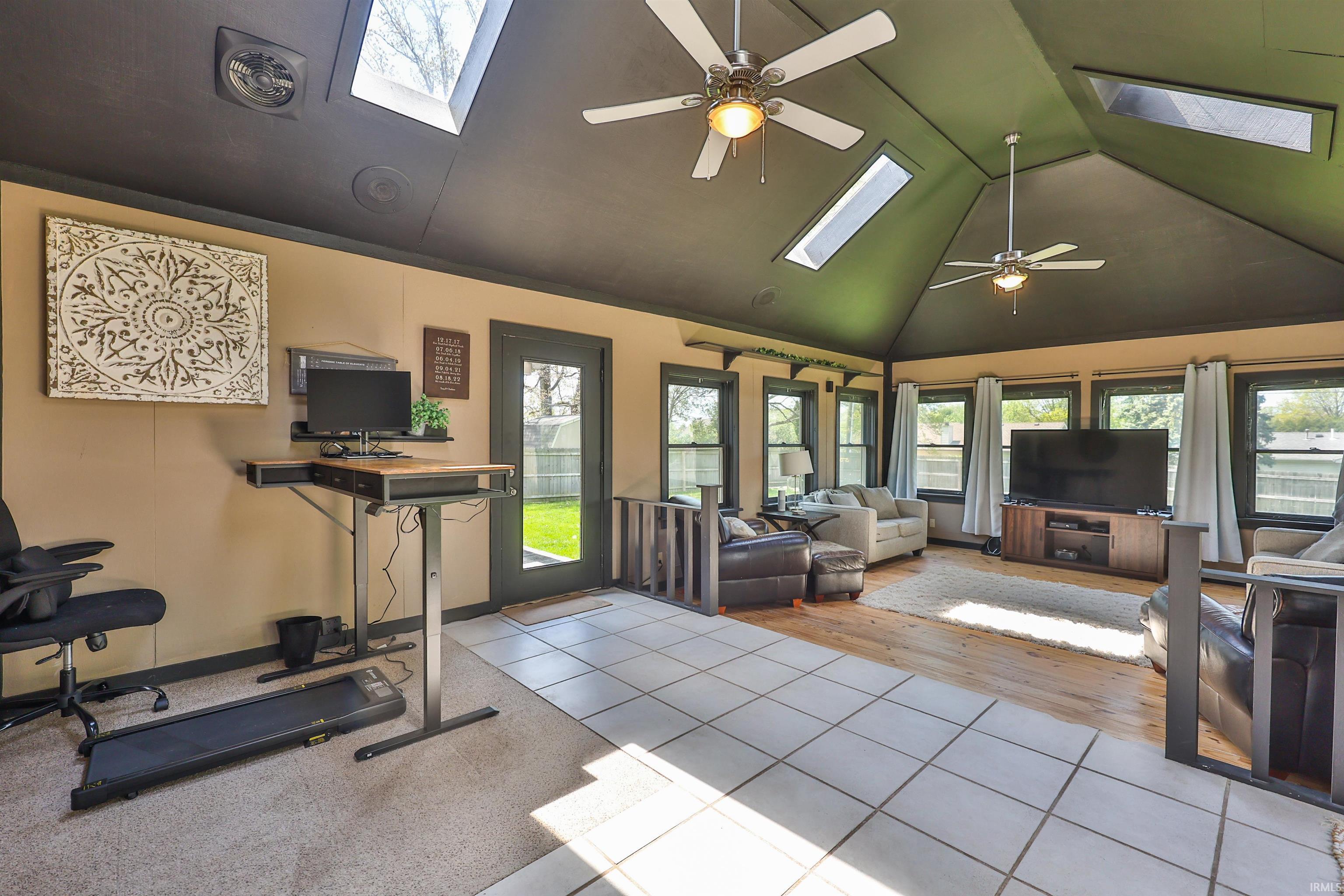 Vaulted ceiling room featuring multiple skylights and ceiling fans