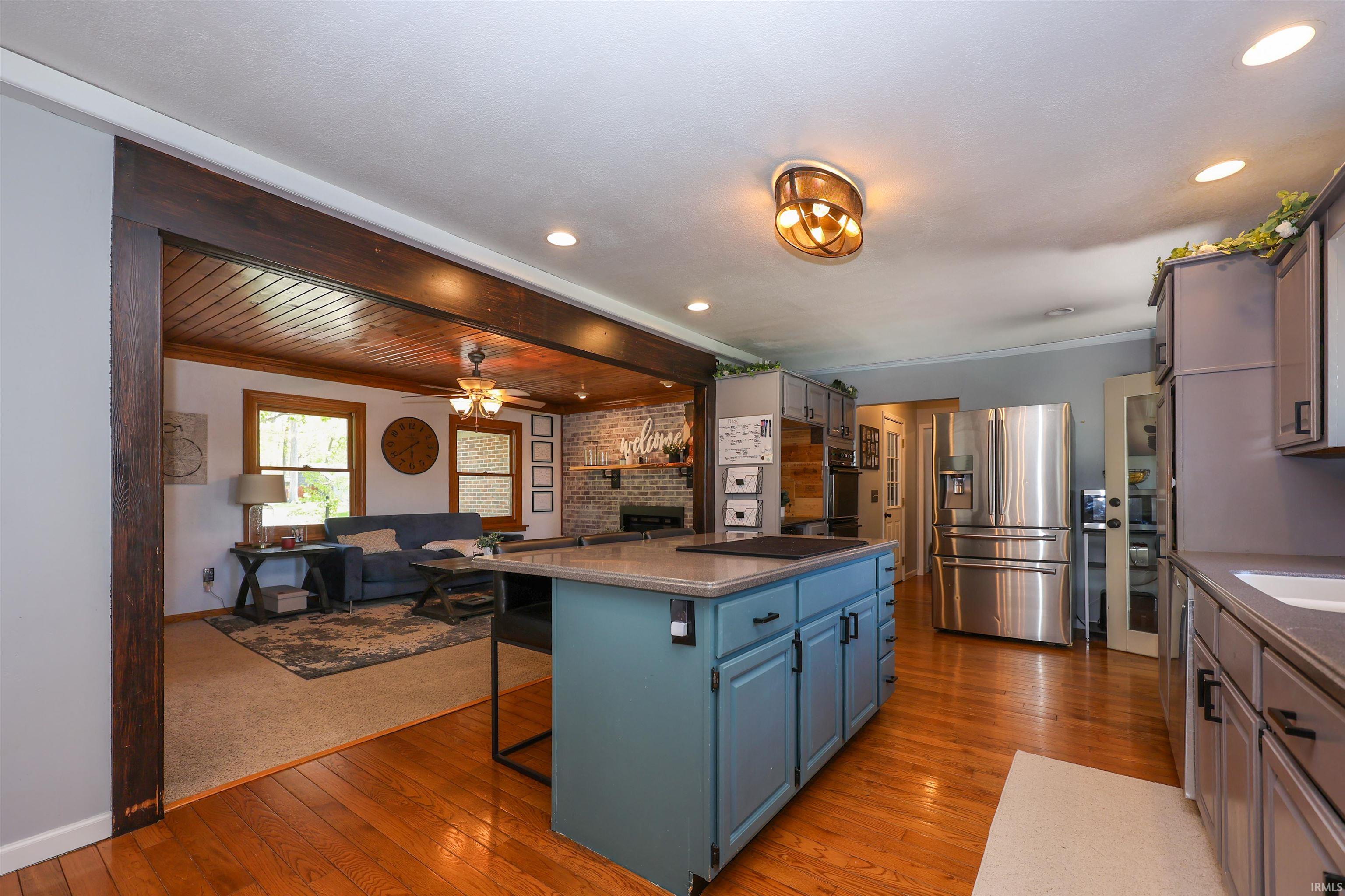Kitchen featuring wood-finish flooring, a central island with blue cabinetry, and stainless steel appliances