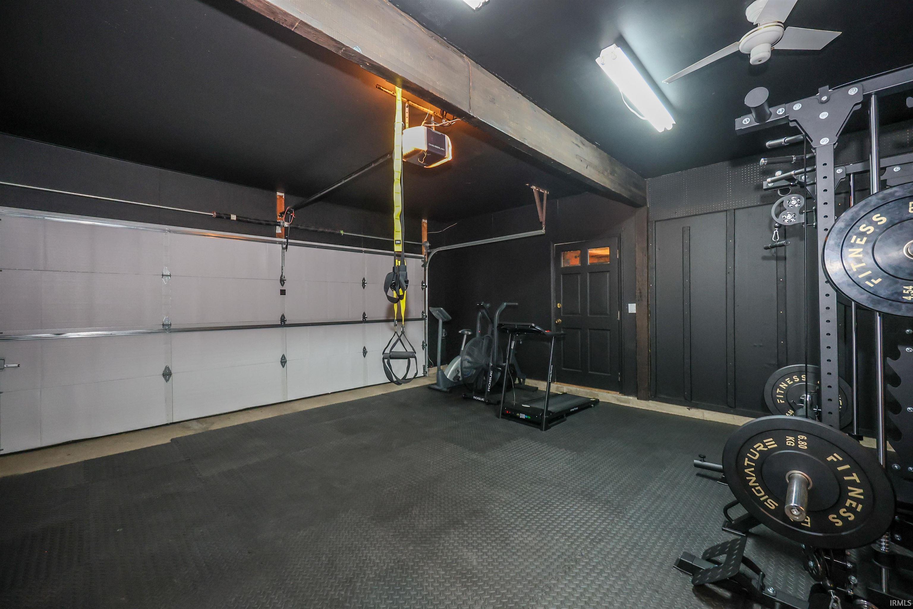 Dedicated space featuring a two-car garage door, dark paneled walls, and a recessed side entry door