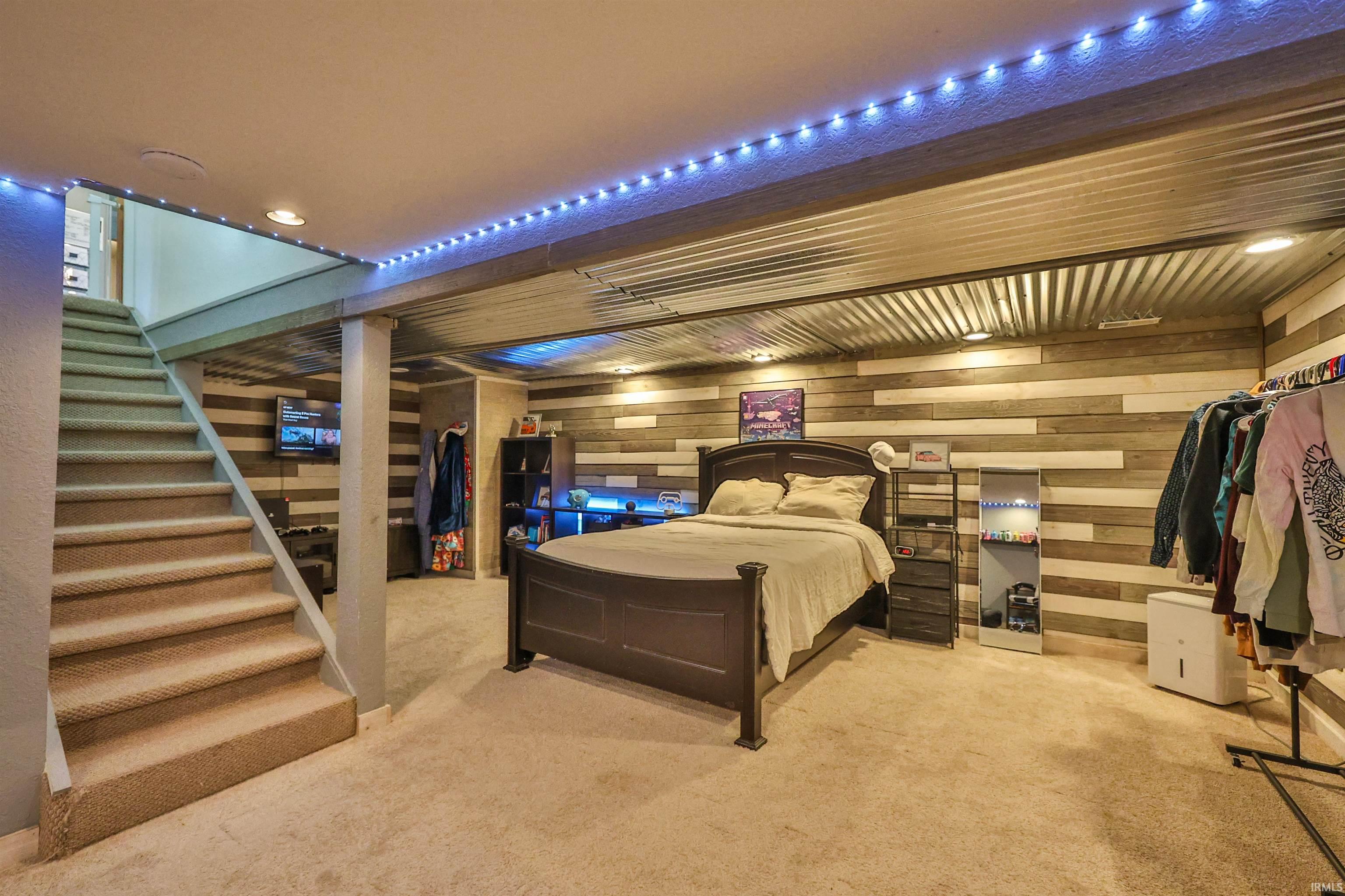 Lower level space featuring textured wood-panel accent walls, corrugated metal ceiling, recessed lighting, and carpeted flooring