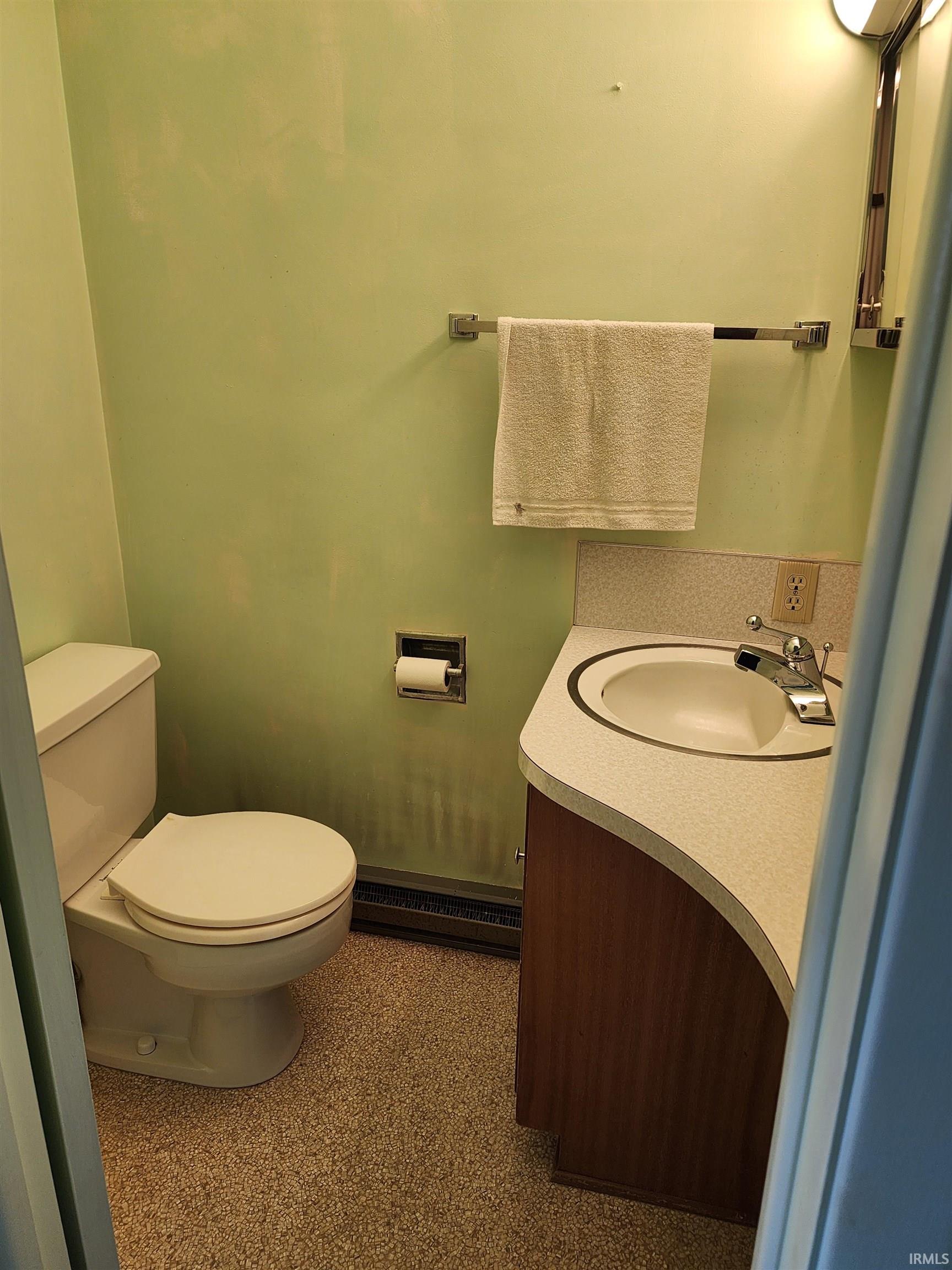 Bathroom featuring a white toilet, speckled flooring, and a wood-finish vanity with a built-in sink