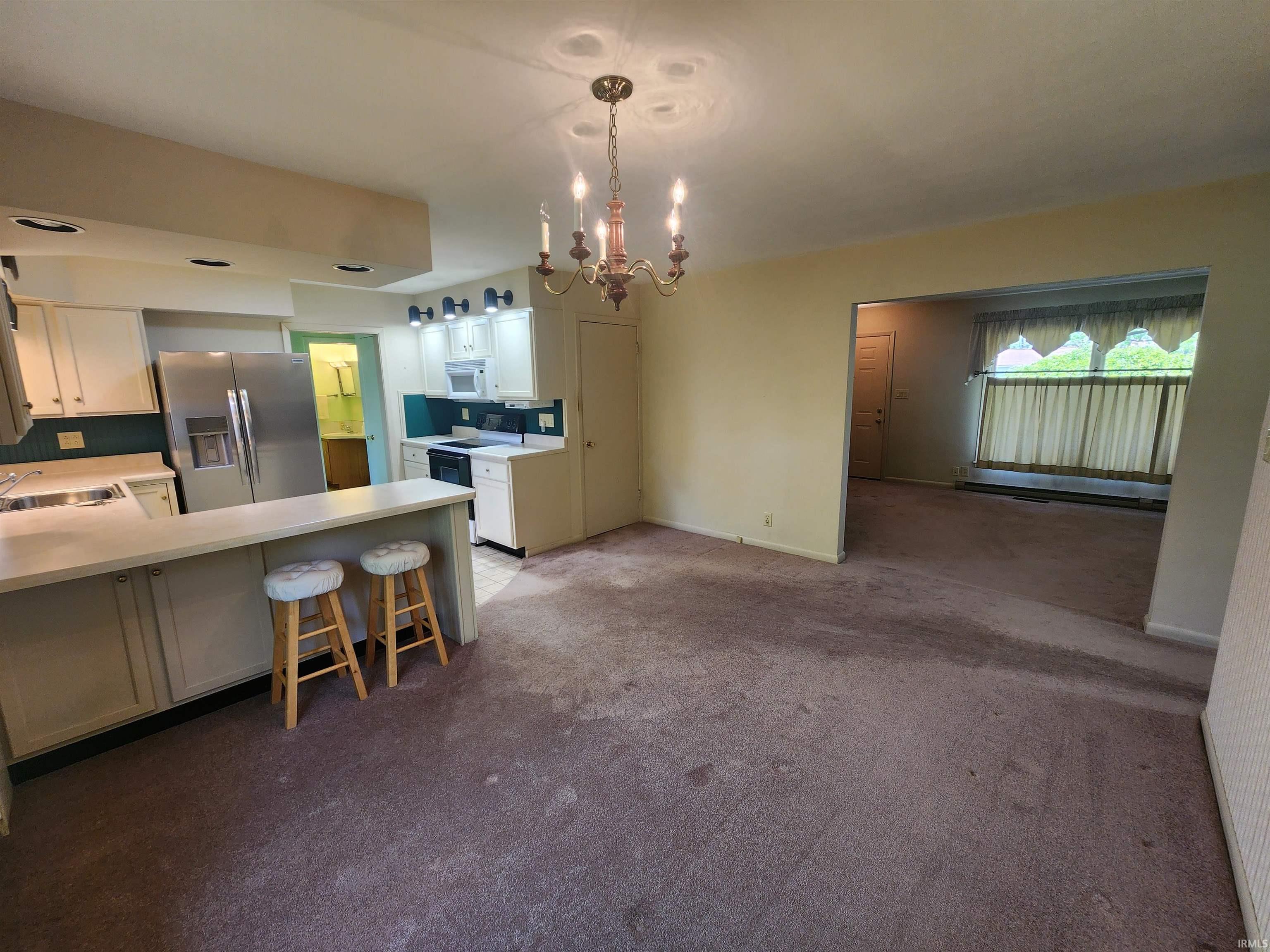 Kitchen featuring white cabinetry, a built-in stainless steel refrigerator, white countertops, and a breakfast bar