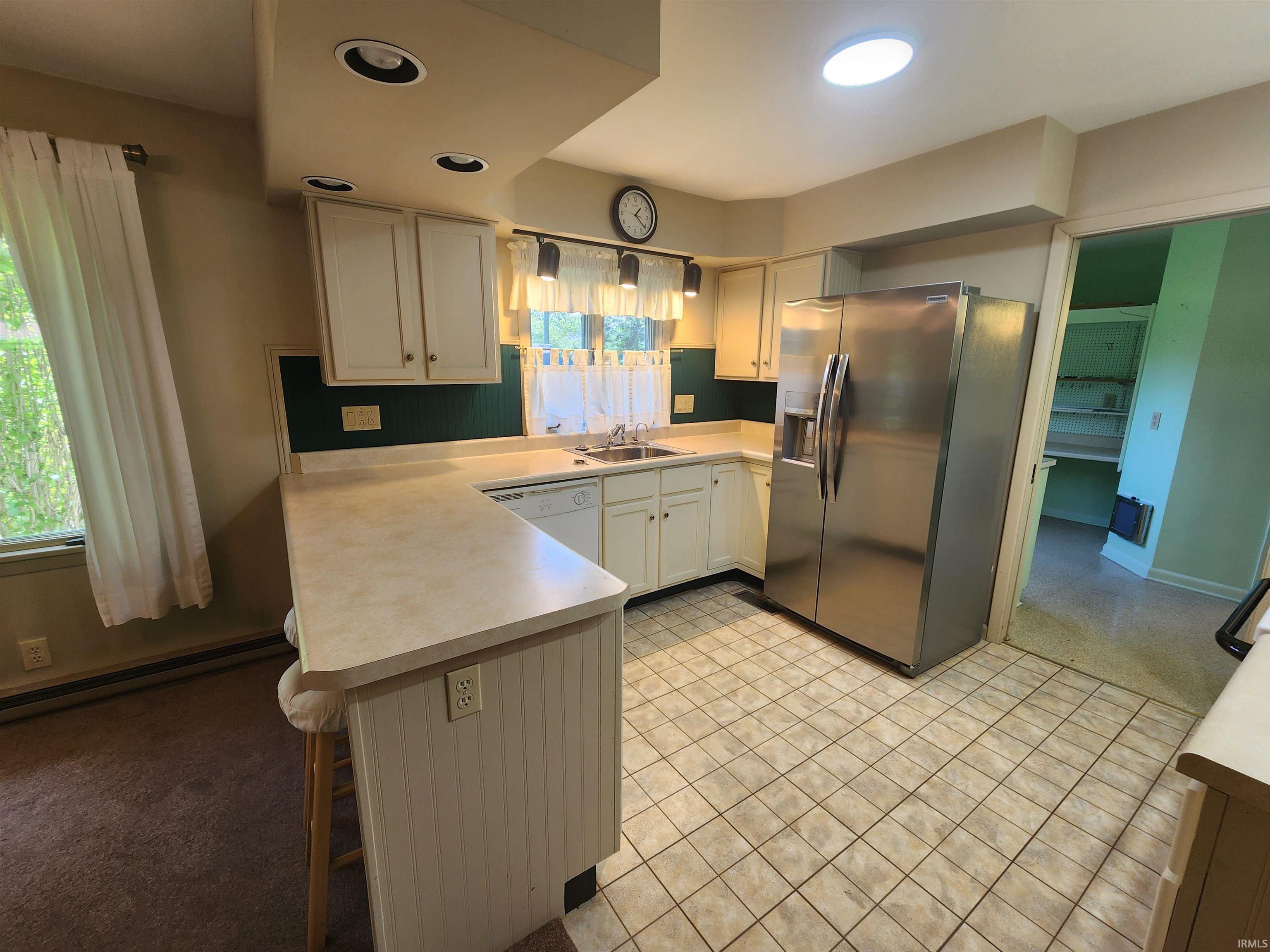 Kitchen featuring white cabinetry, light-toned countertops, and a stainless steel refrigerator