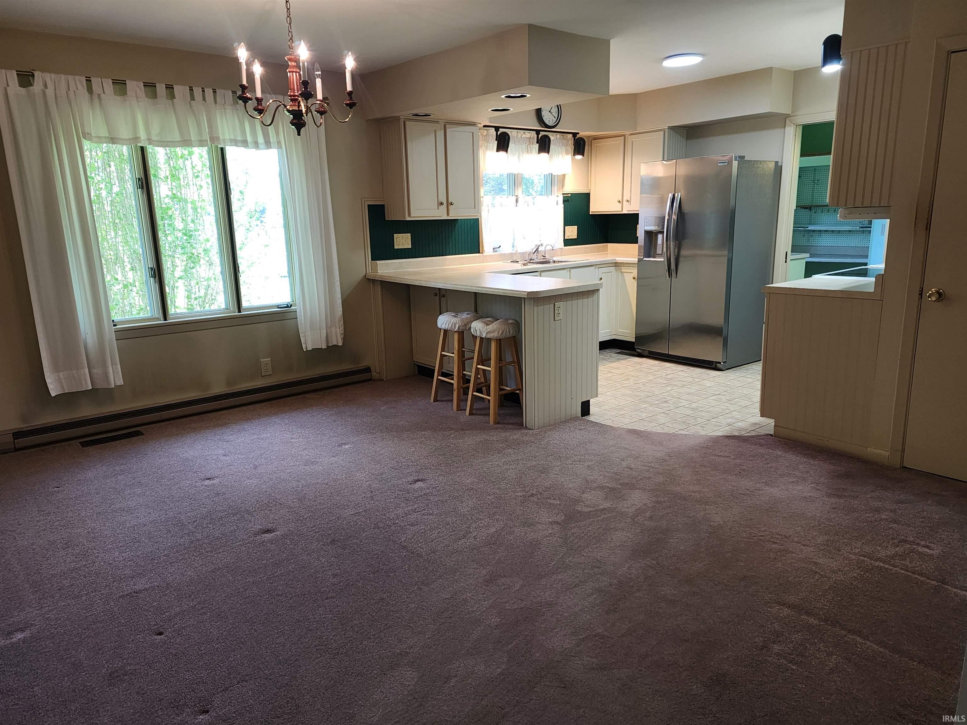 Open concept kitchen and dining area featuring a breakfast bar, white cabinetry, stainless steel refrigerator, and recessed lighting