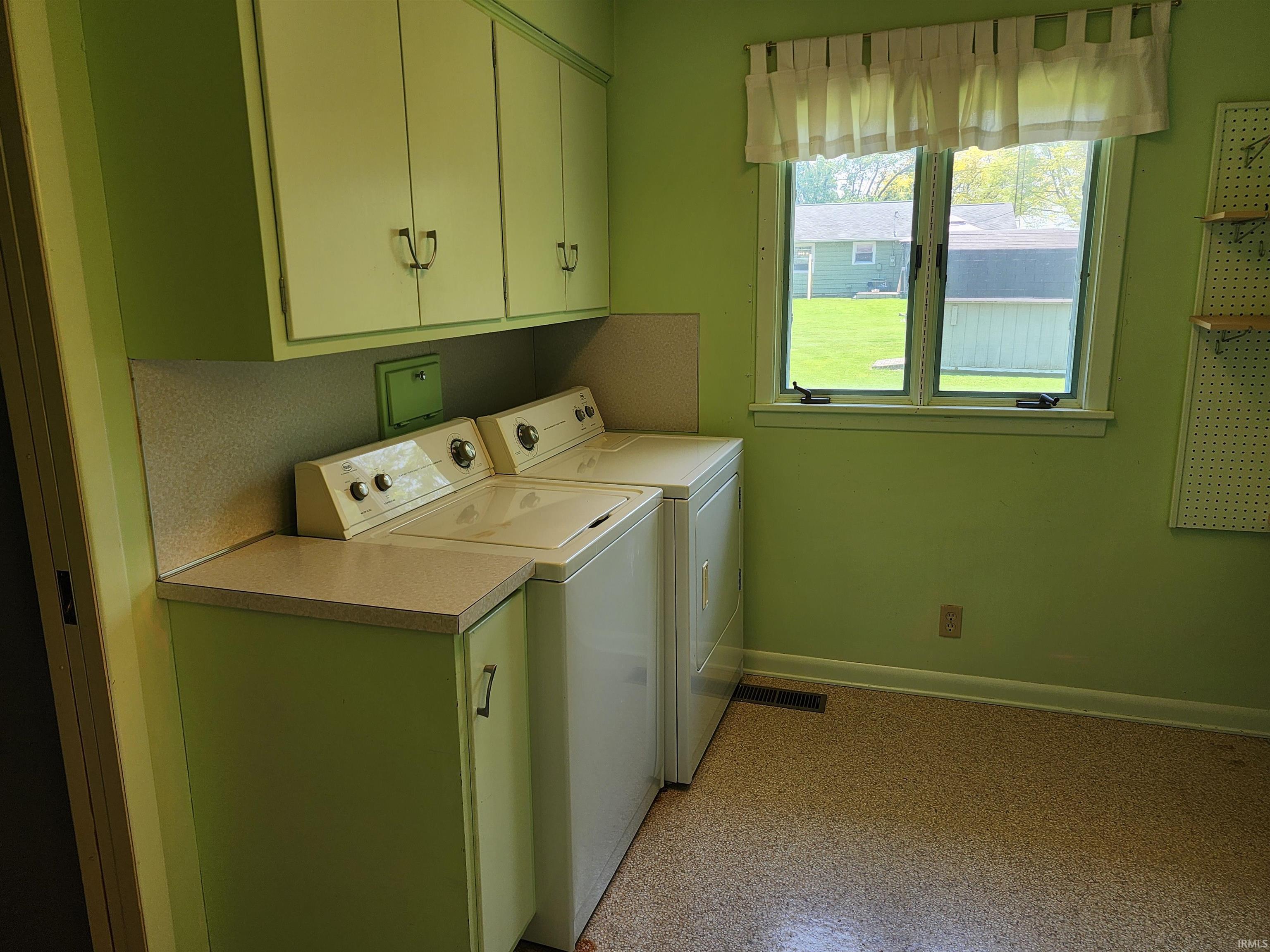 Dedicated utility room featuring upper and lower cabinetry, a countertop work surface, and a window providing exterior visibility