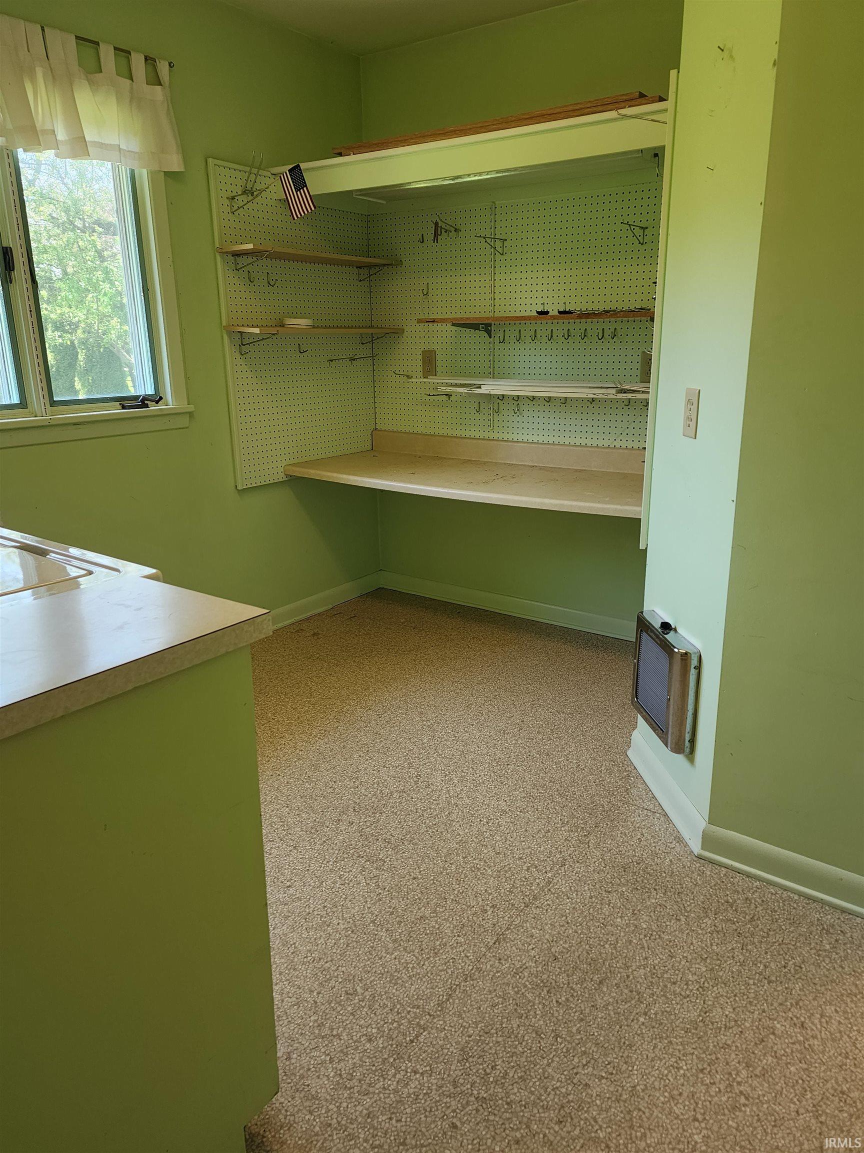 Dedicated workspace featuring a built-in desk, integrated pegboard shelving, and overhead storage