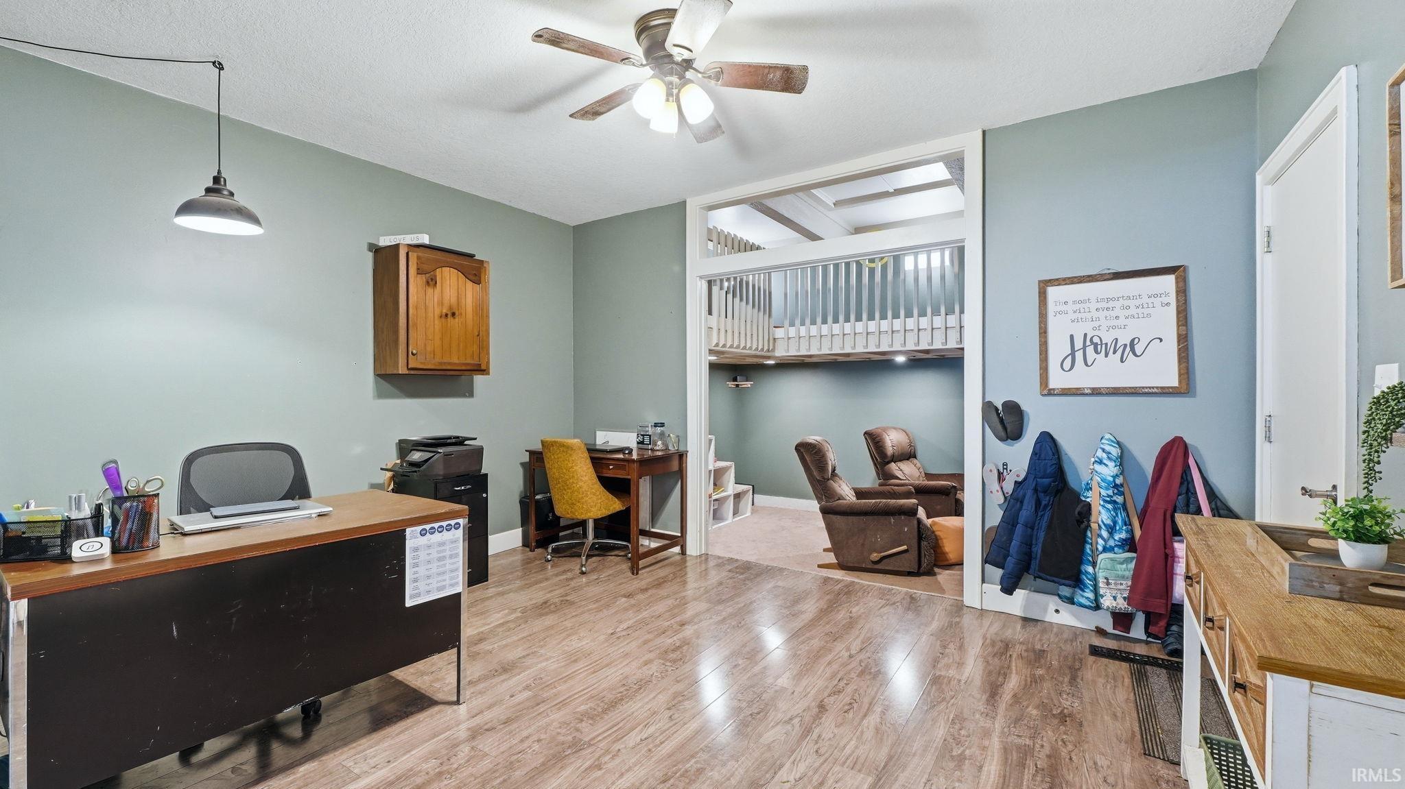 Spacious room with wood-finish flooring, light blue-green walls, and a ceiling fan